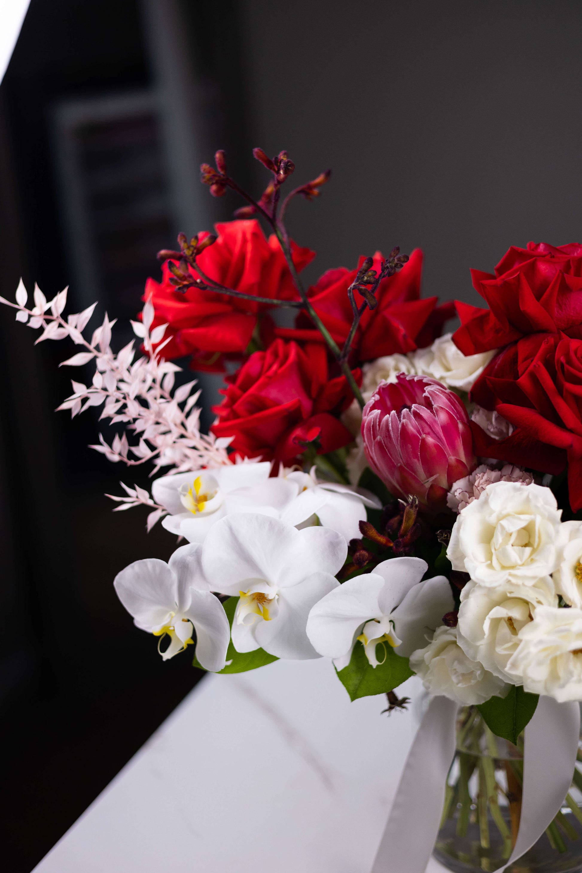 Bouquet of red and white flowers in a clear vase on a dark background