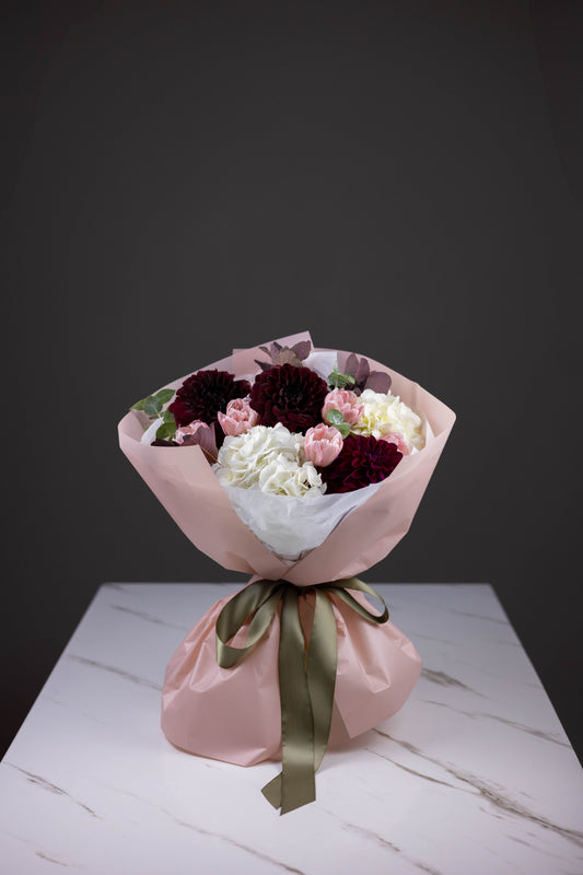 Blush-wrapped bouquet featuring burgundy dahlias, pink tulips, and ivory hydrangeas in Charlotte, NC