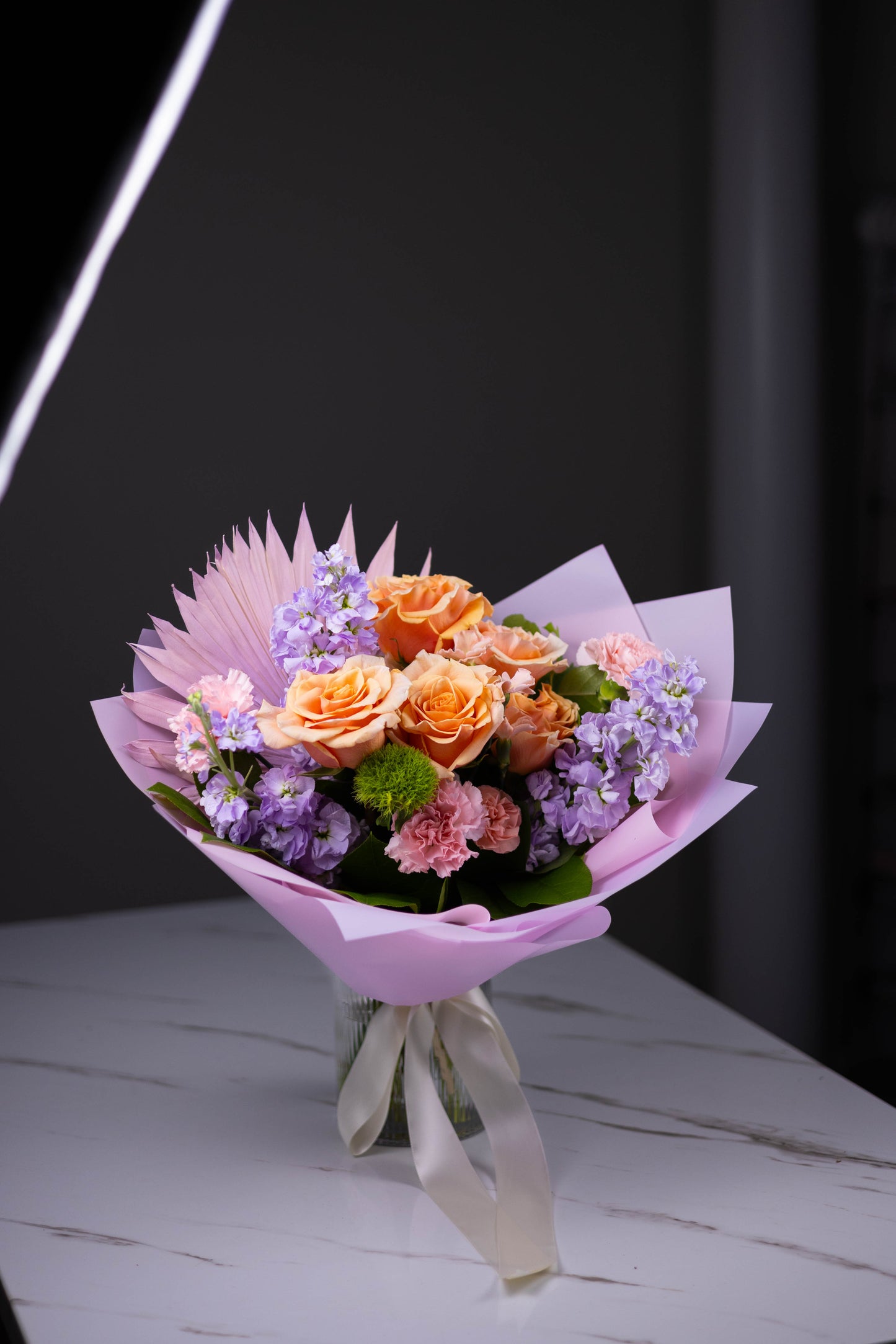 Bouquet of flowers wrapped in pink paper on a dark background