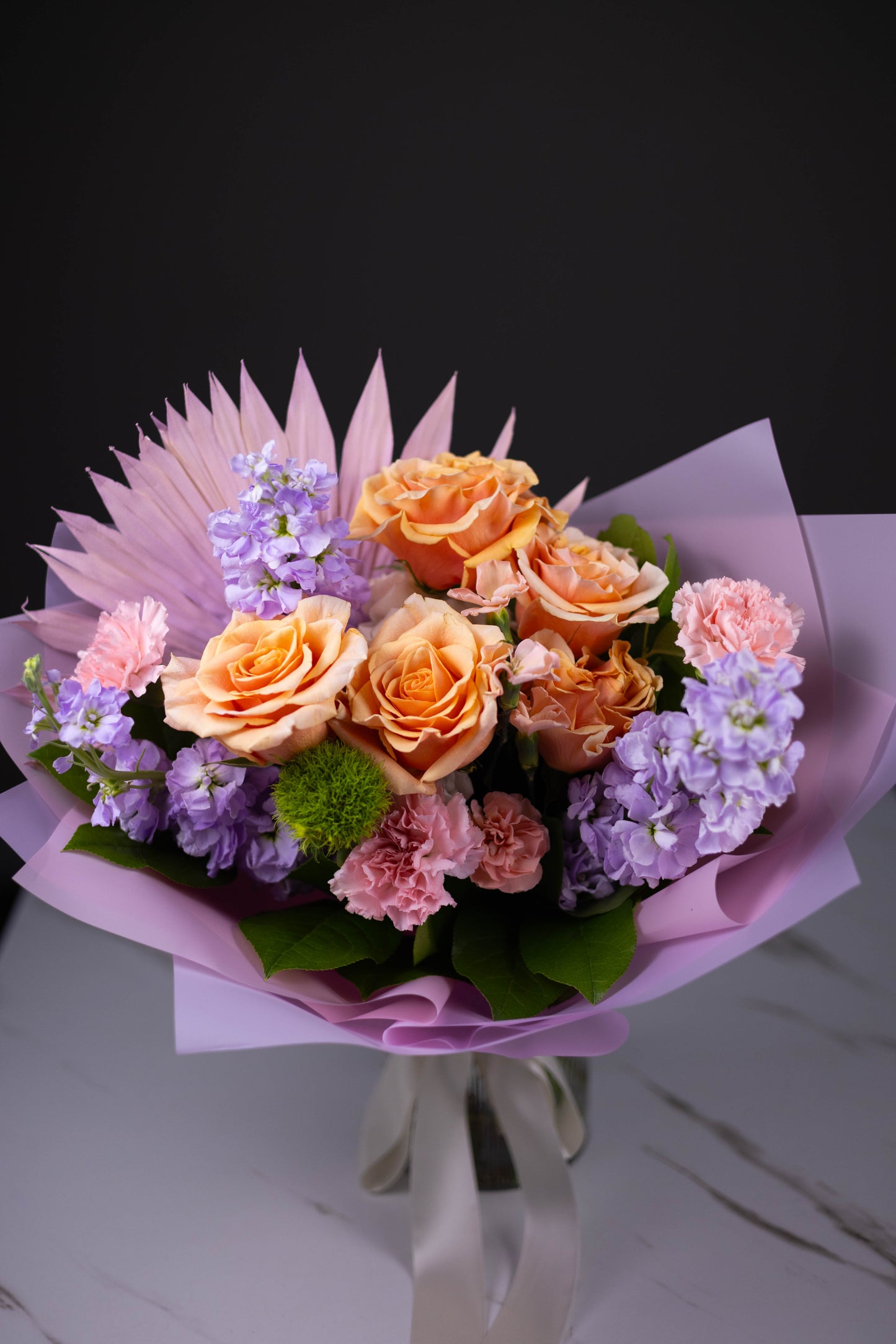 Bouquet of flowers with pink and purple accents on a dark background