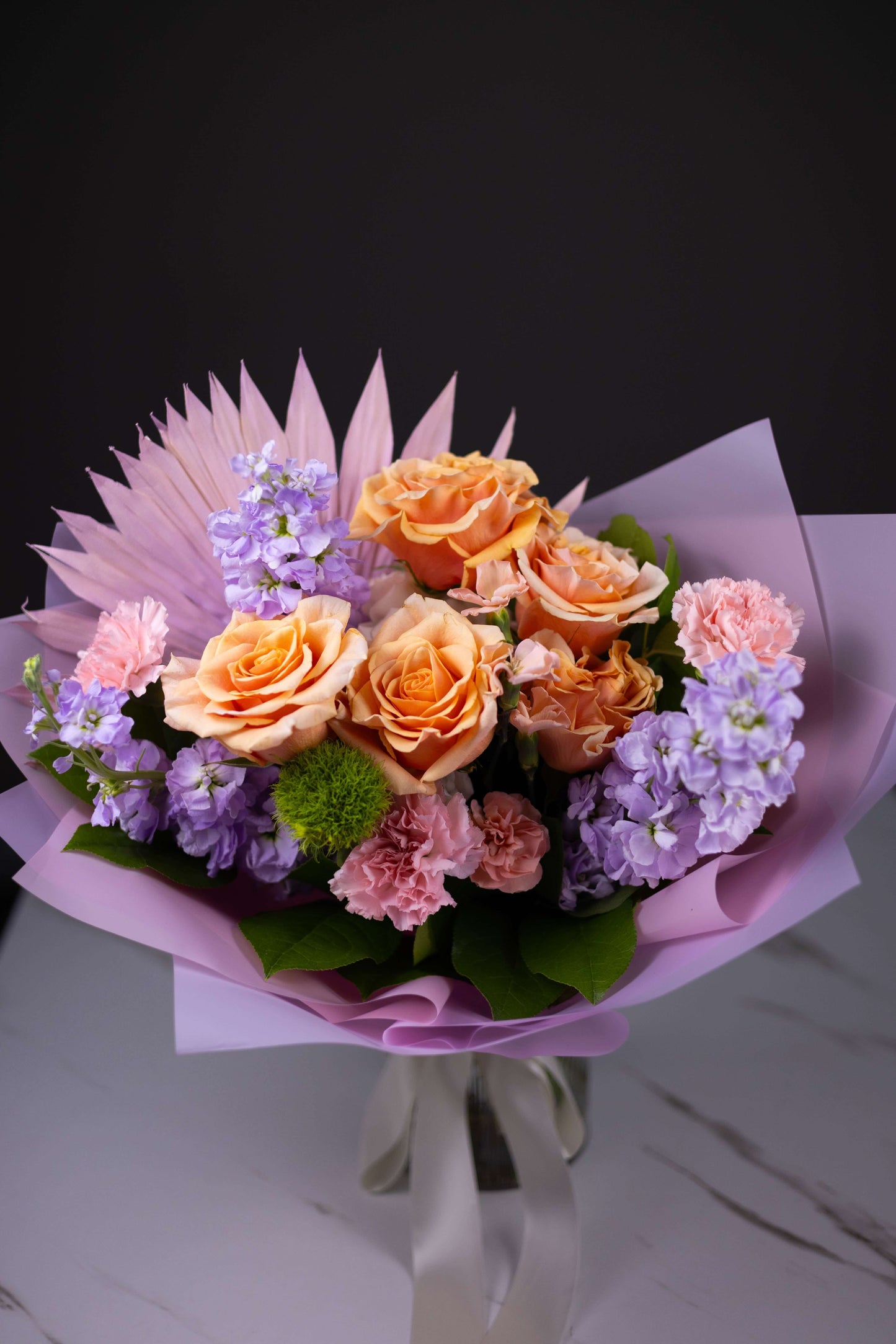 Bouquet of flowers with pink and purple accents on a dark background