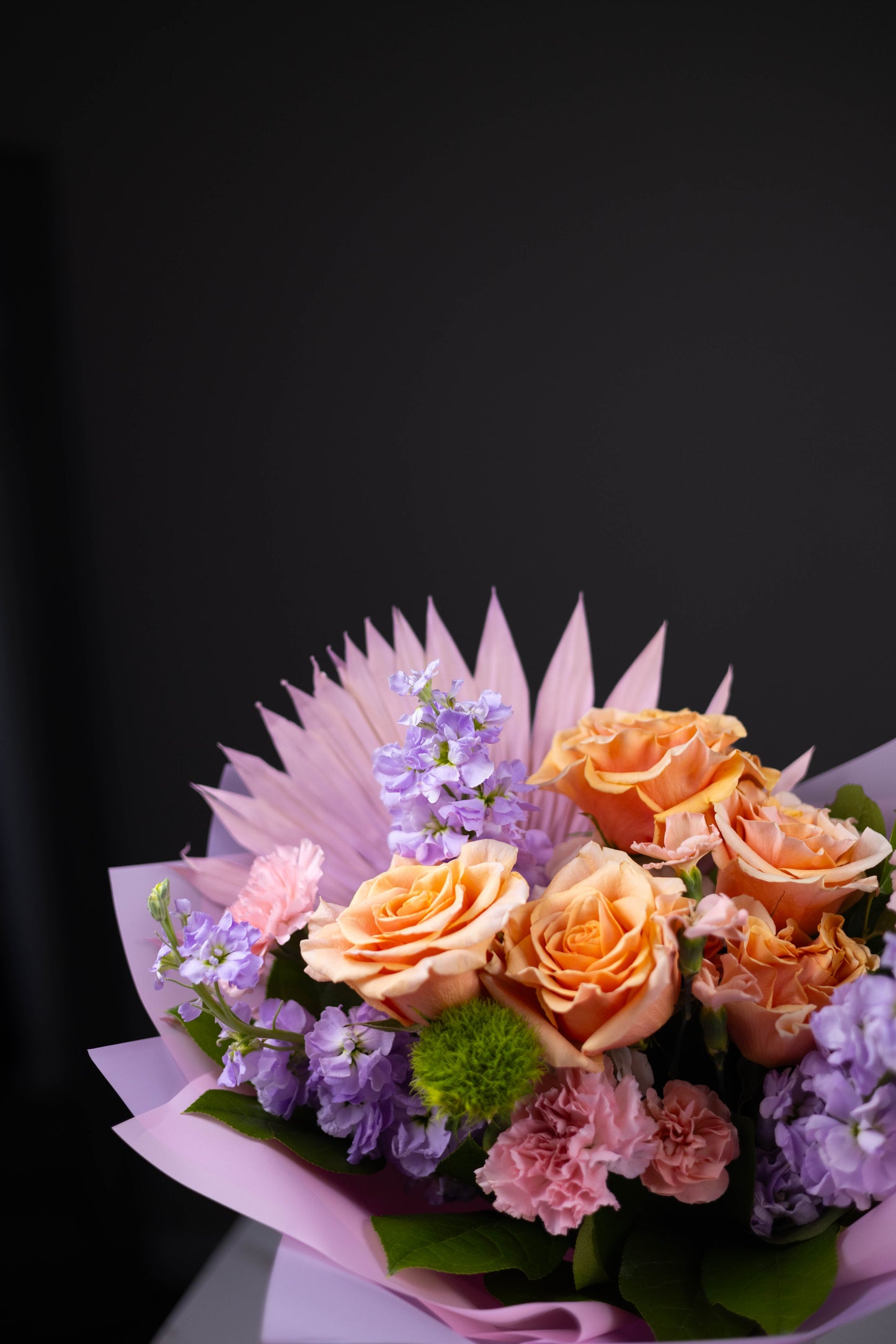 Bouquet of flowers with orange roses and purple hydrangeas on a black background