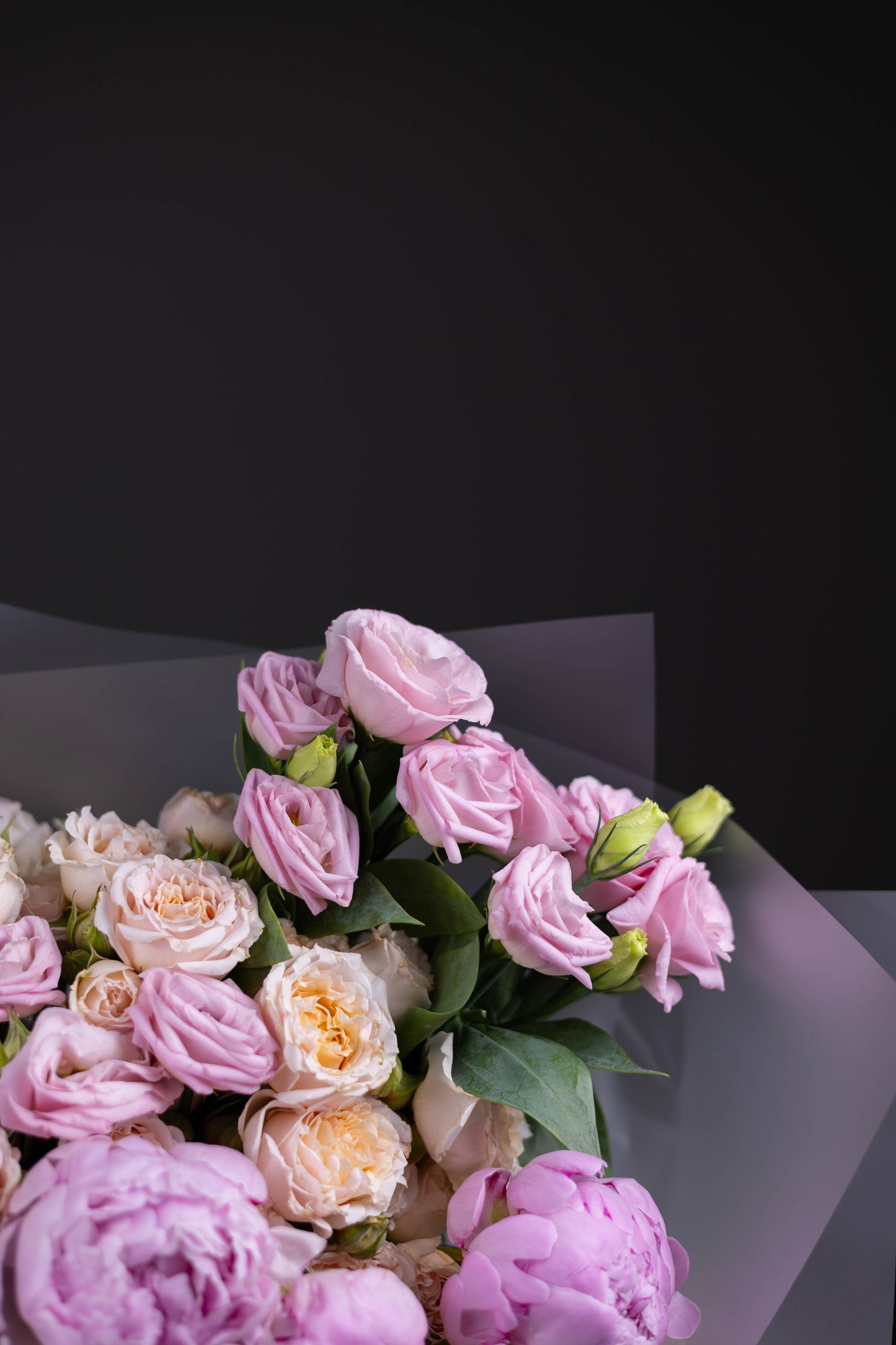 Top view of a pastel-toned flower bouquet, showcasing pink lisianthus and full-bodied peonies with creamy roses.