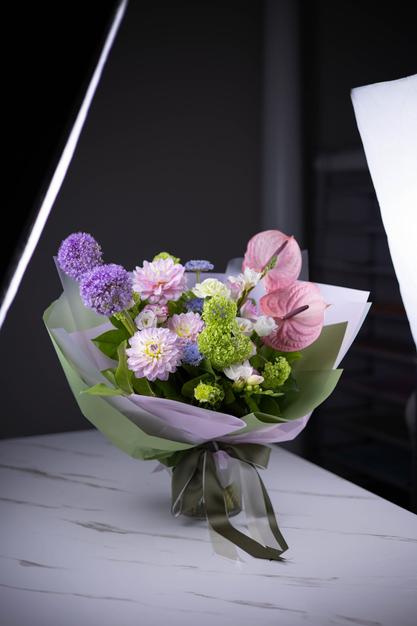 Angled view of the pastel bouquet showcasing anthuriums and dahlias