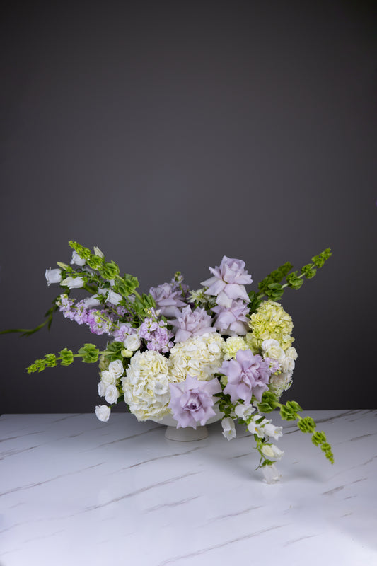 Floral arrangement in a glass vase on a white surface with a dark gray background
