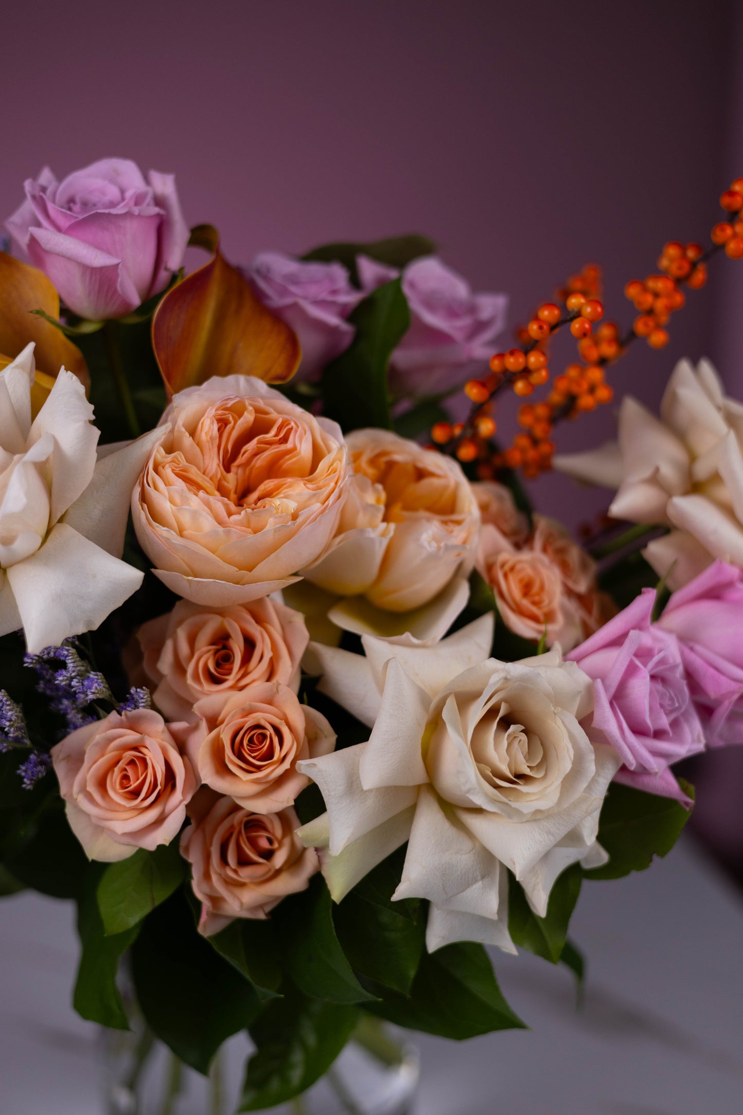Bouquet of flowers with pink, orange, and white roses on a purple background