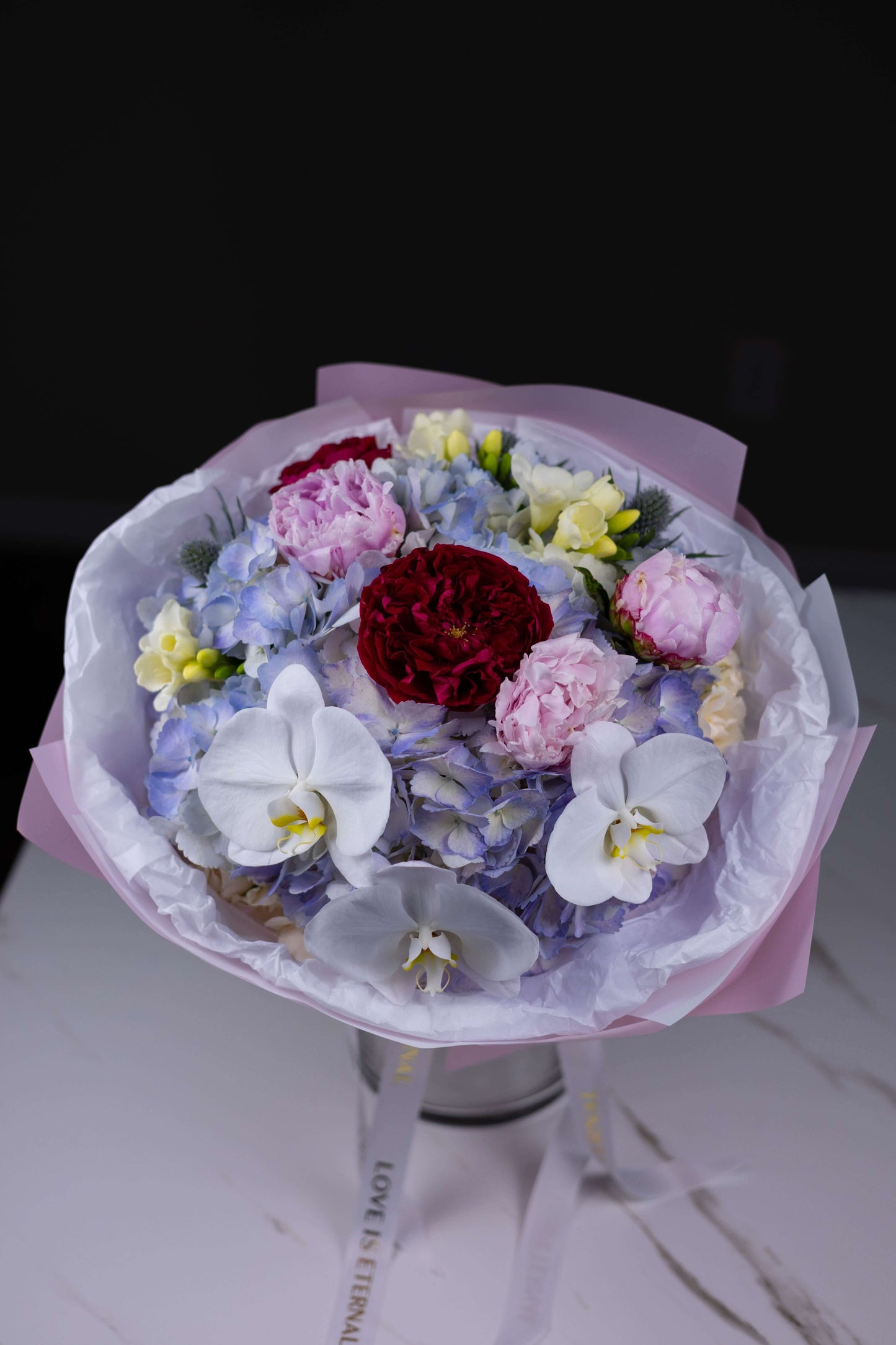 High-end bouquet with pastel blooms and striking red center roses – luxury gift flowers NC