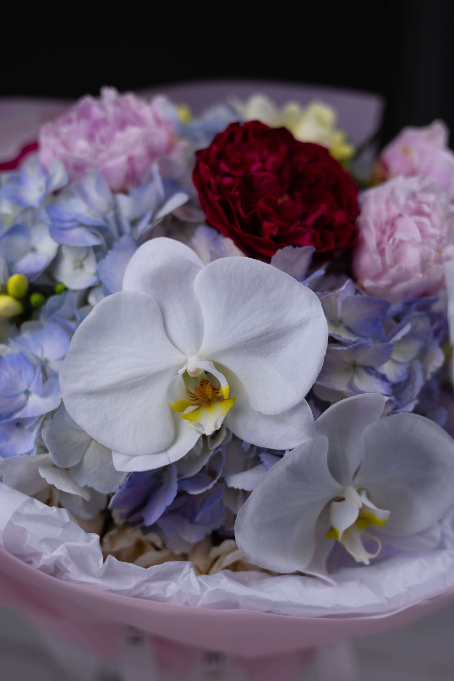 Orchid and hydrangea bouquet in pink wrap for luxury floral delivery Charlotte North Carolina