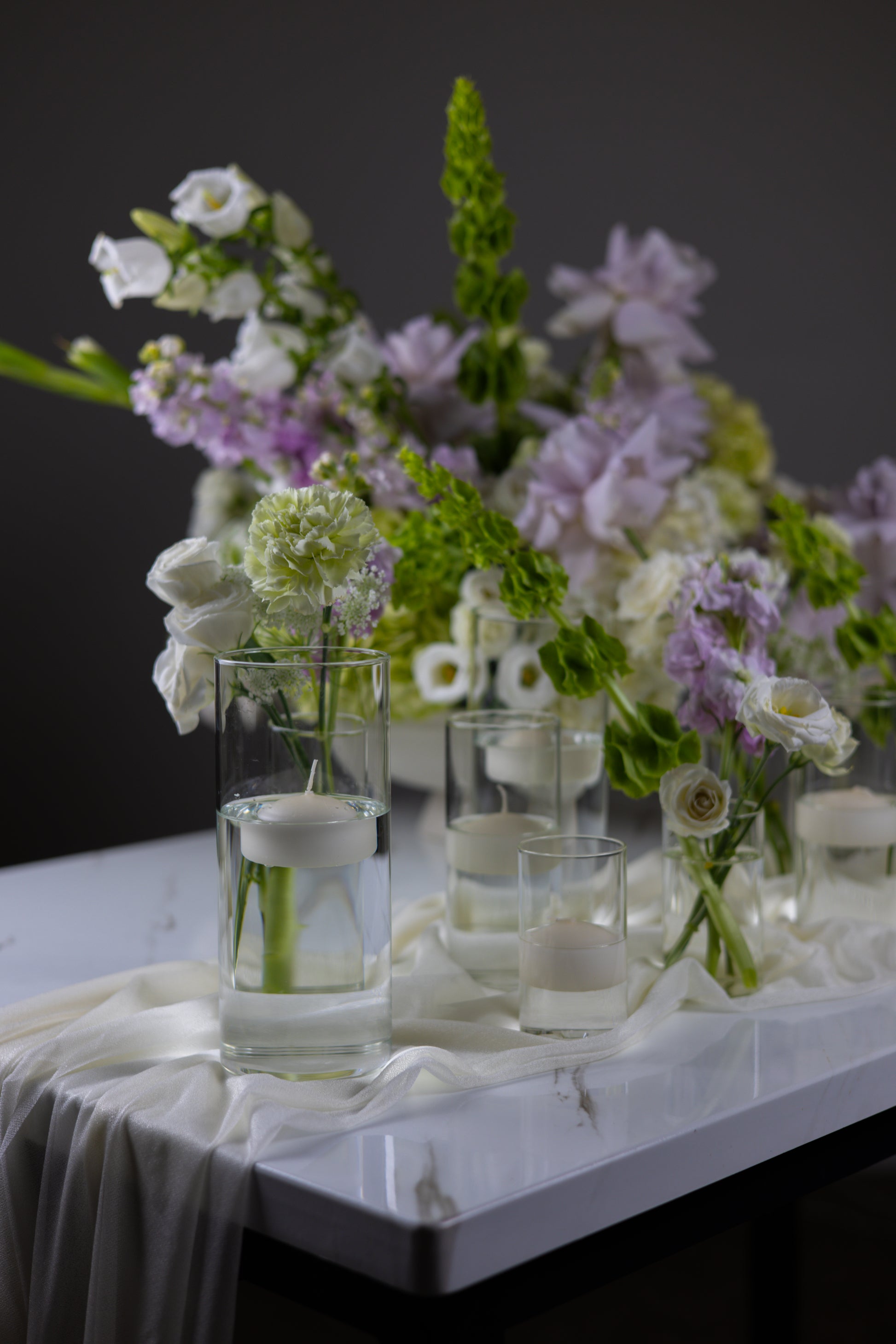Bouquet of flowers with vases on a table against a dark background