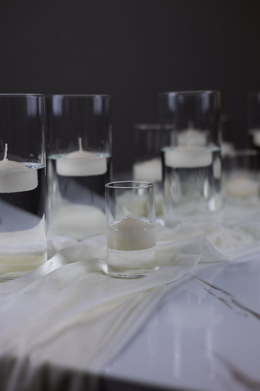 Clear glass candle holders with white candles on a dark background