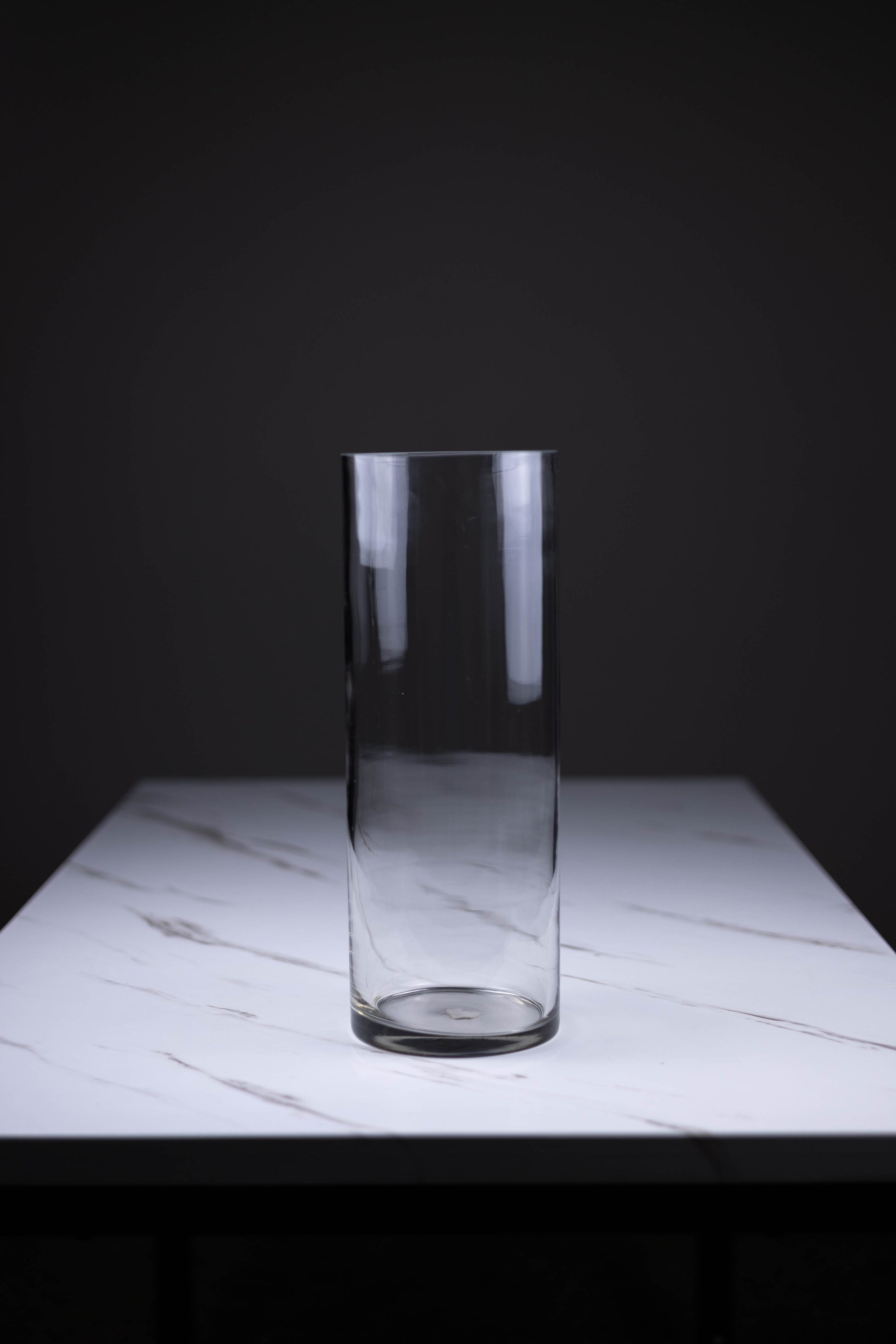 Clear glass vase on a marble surface with a dark background