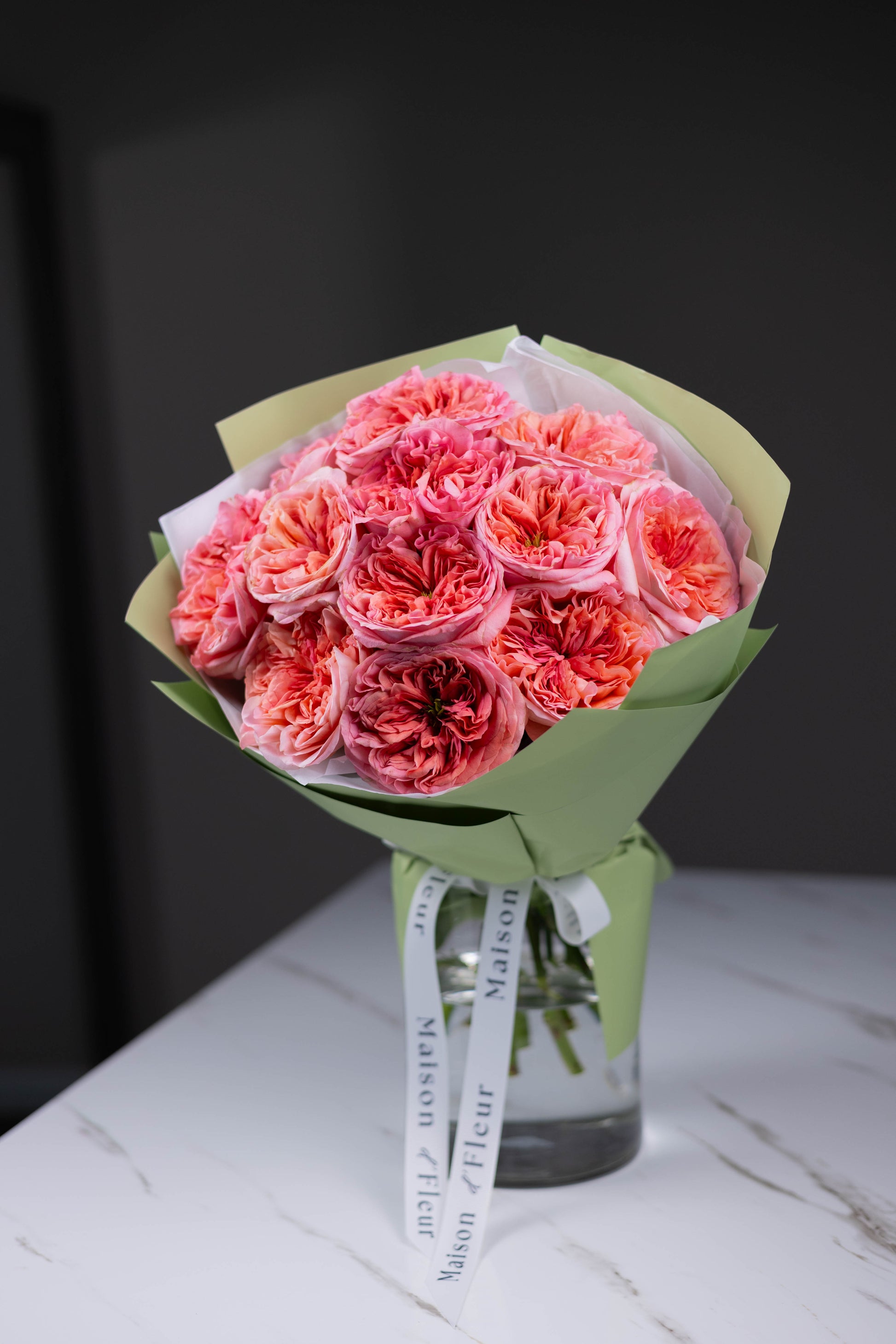 Maison d’Fleur coral rose bouquet with signature wrapping and ribbon