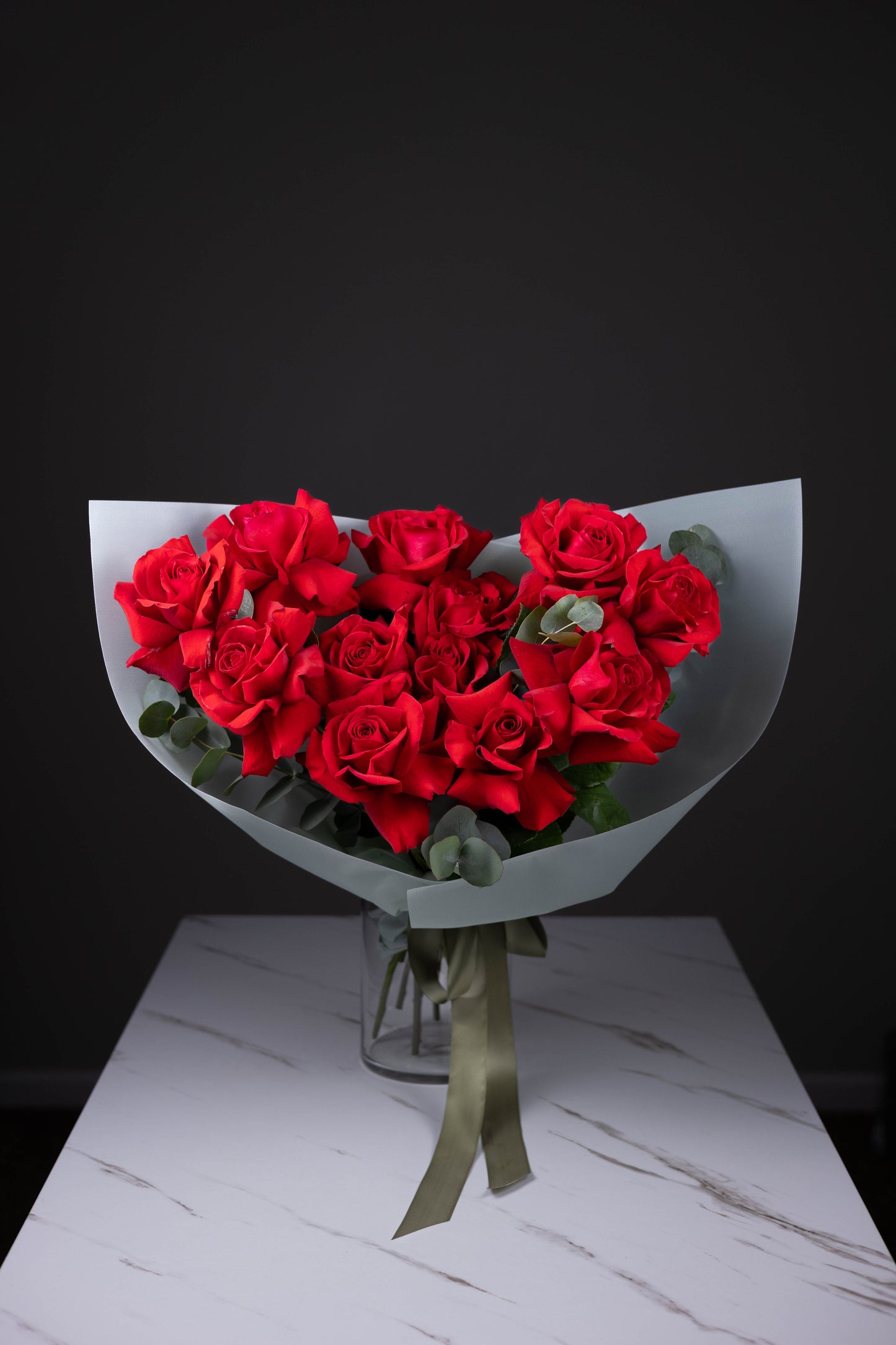 Full bouquet of 25 red roses arranged in a dome shape in a glass vase