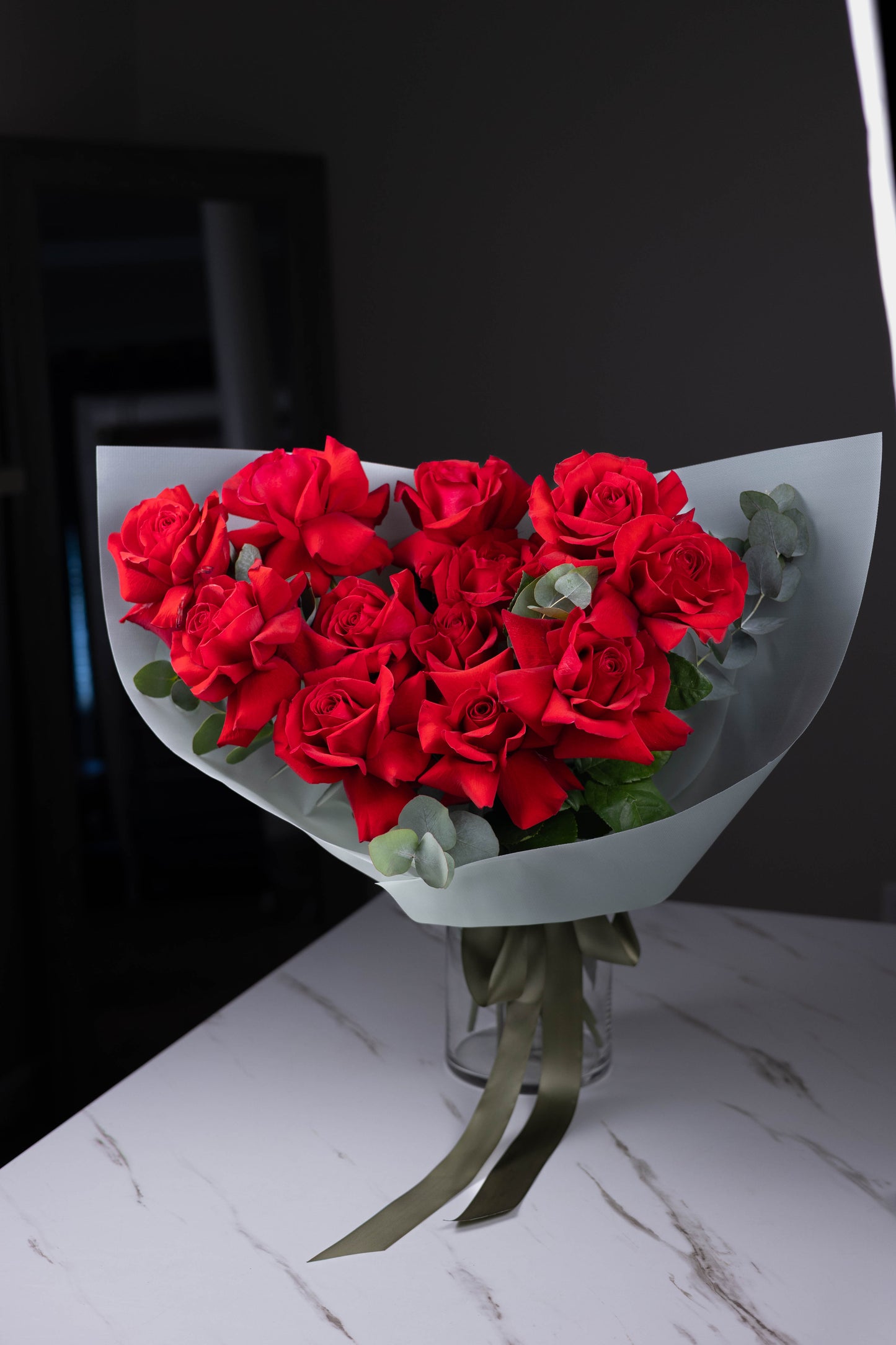 Studio shot of a lush red rose bouquet with eucalyptus on a dark background