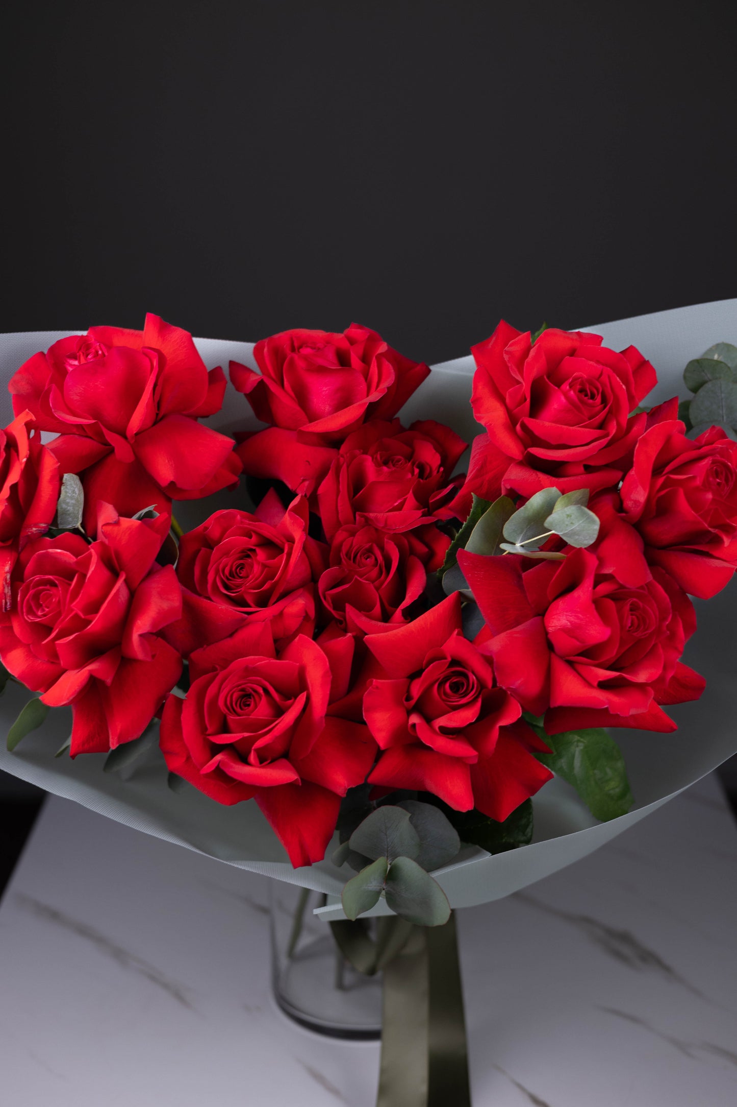 Bouquet of red roses on a white surface with a black background