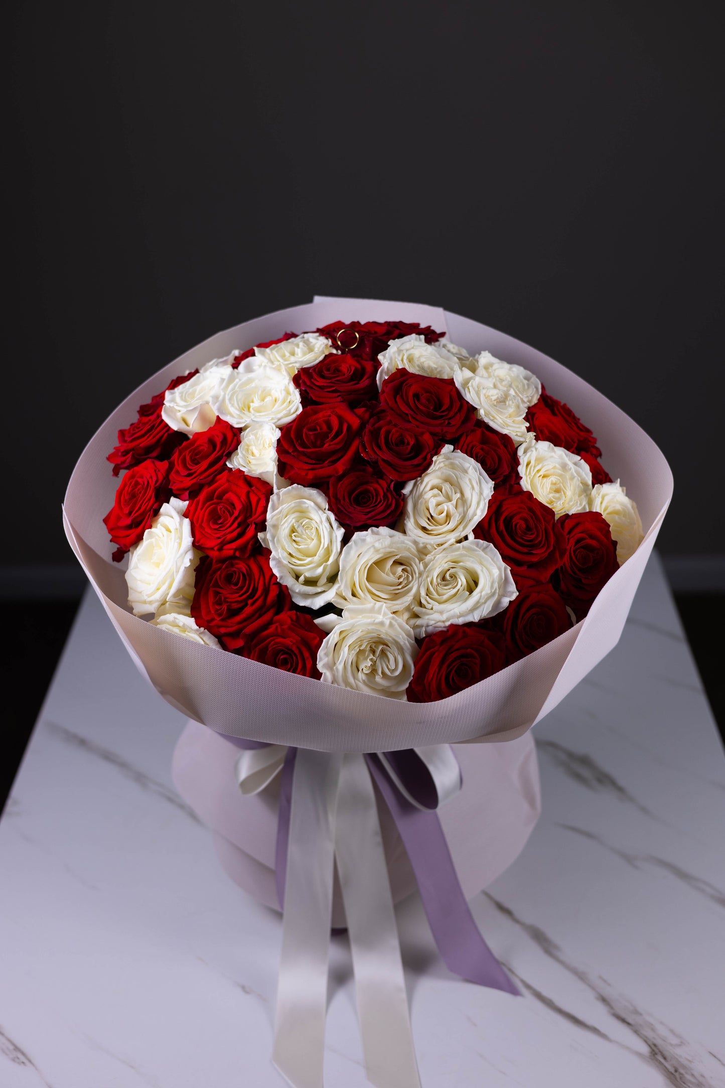 Bouquet of red and white roses on a marble surface with a dark background