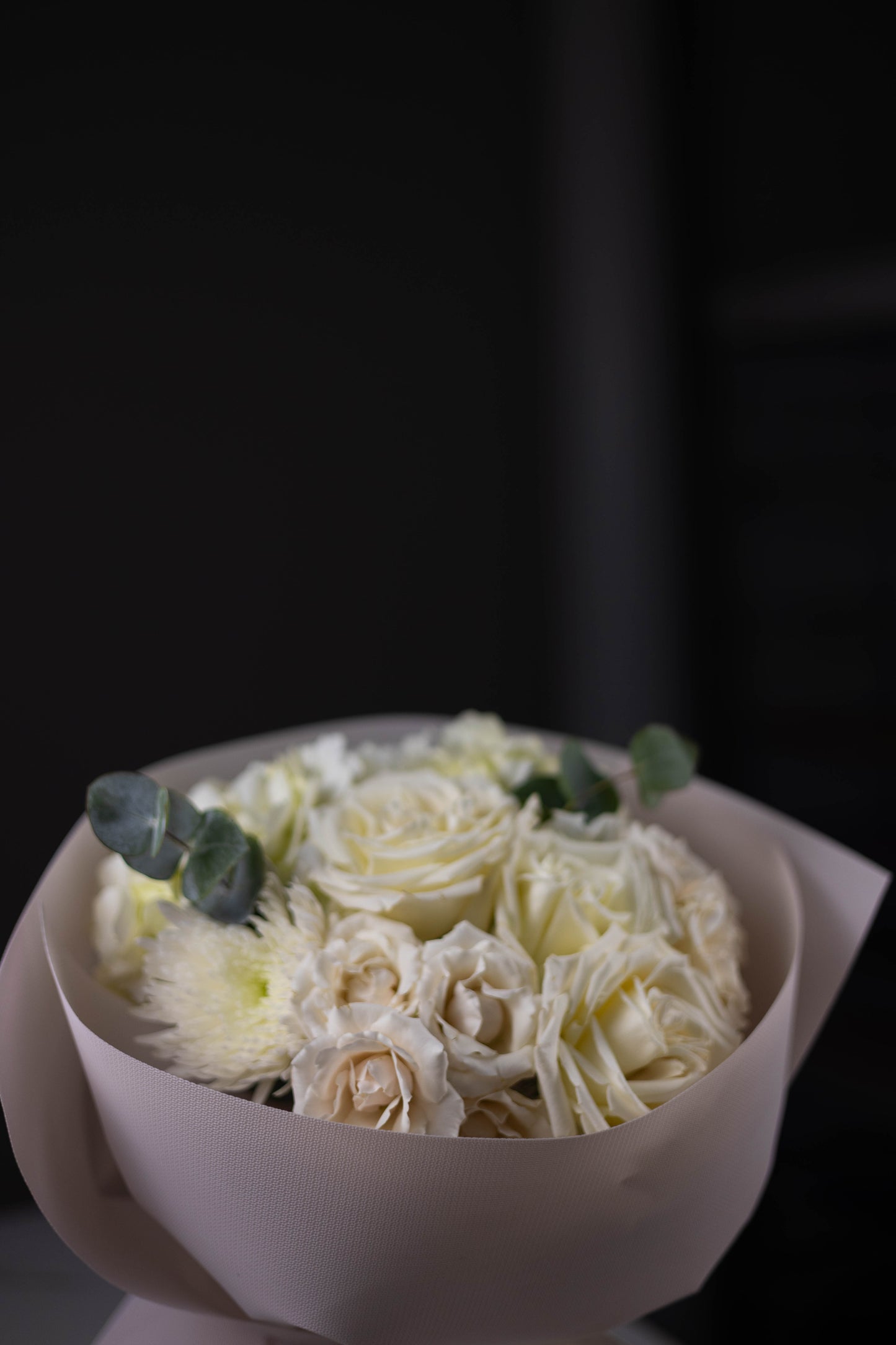 Bouquet of white flowers in a white container on a dark background