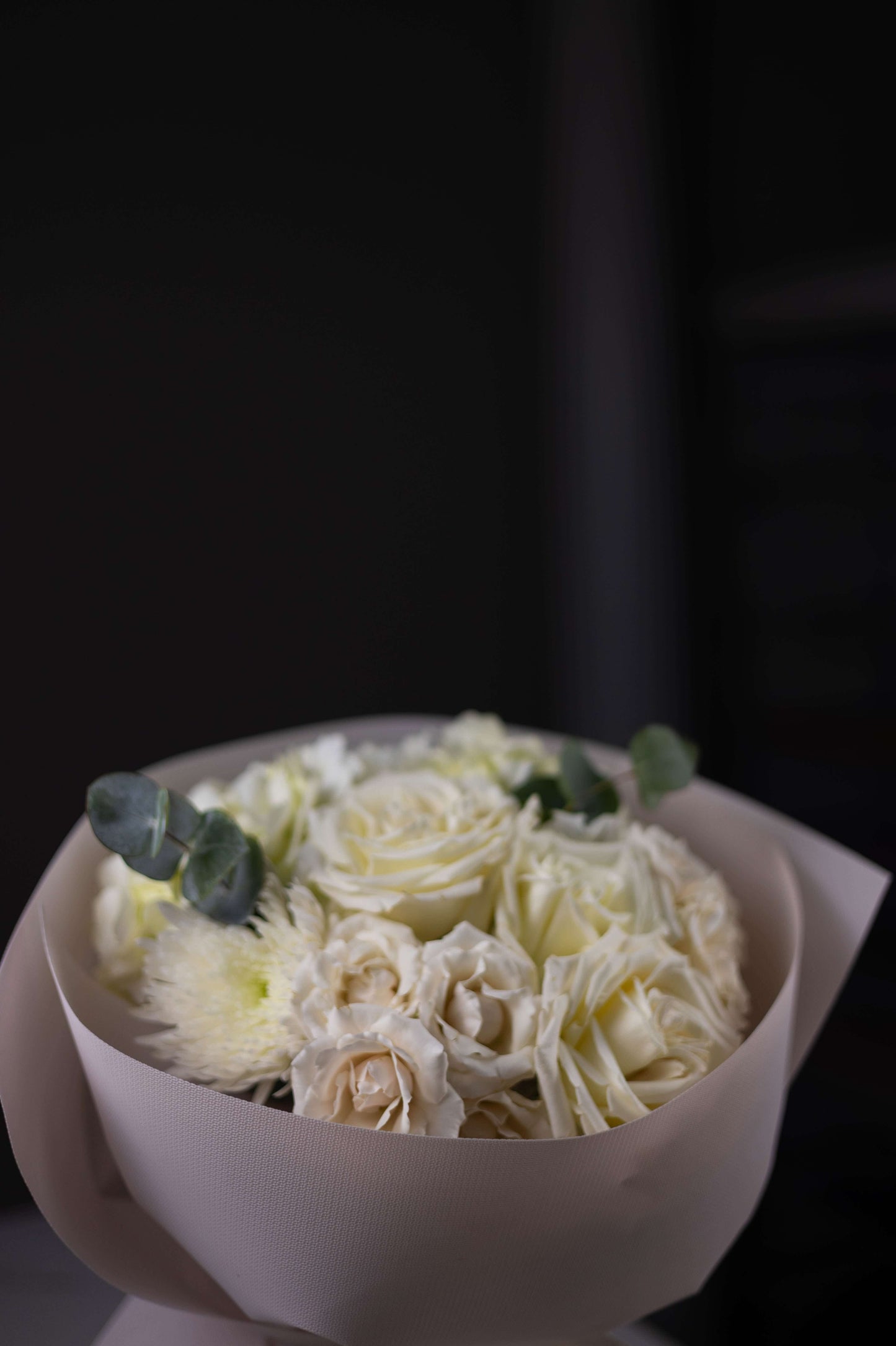 Bouquet of white flowers in a white container on a dark background