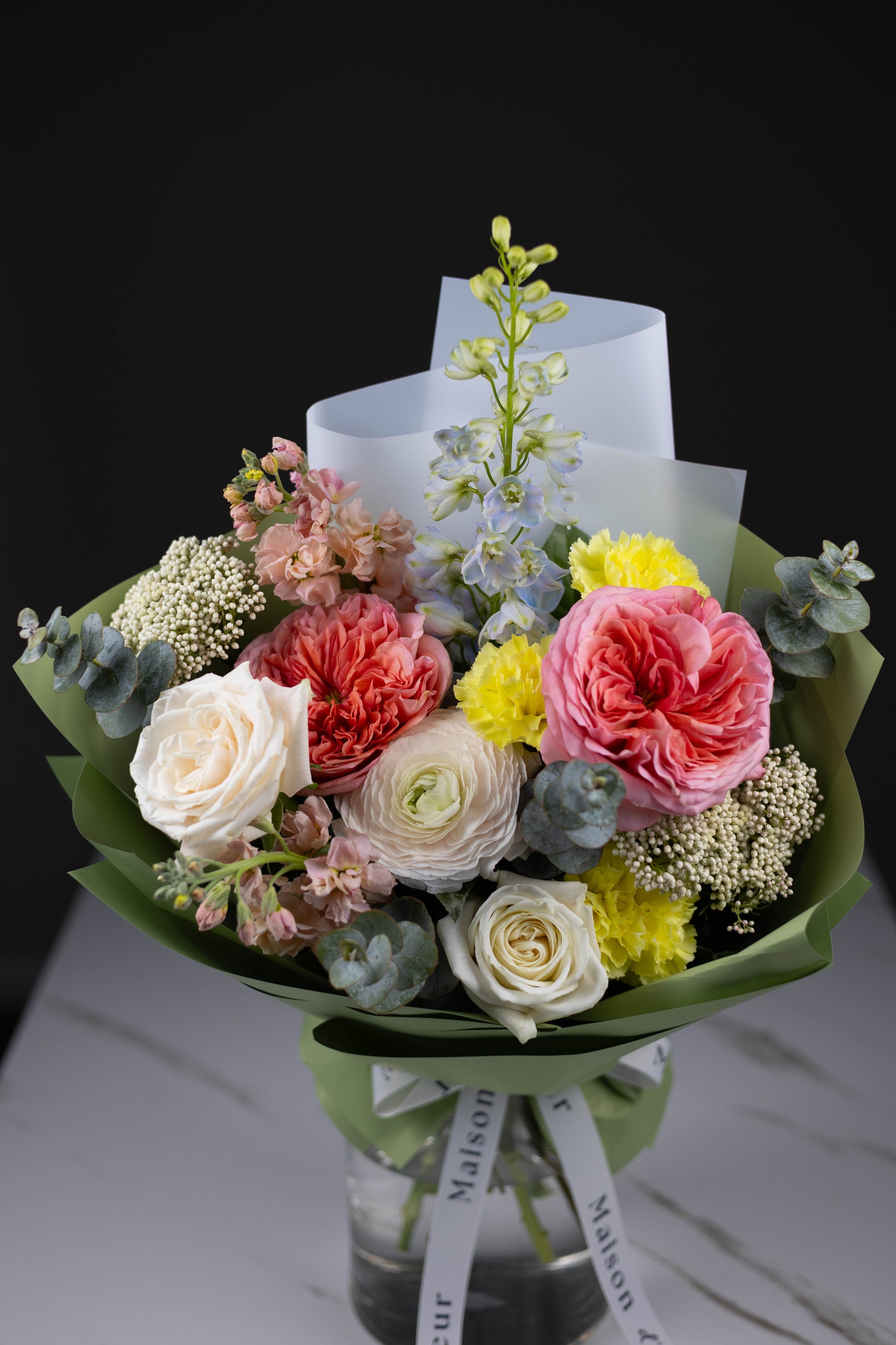 Luxury spring floral arrangement with peach roses, yellow carnations, and delphinium