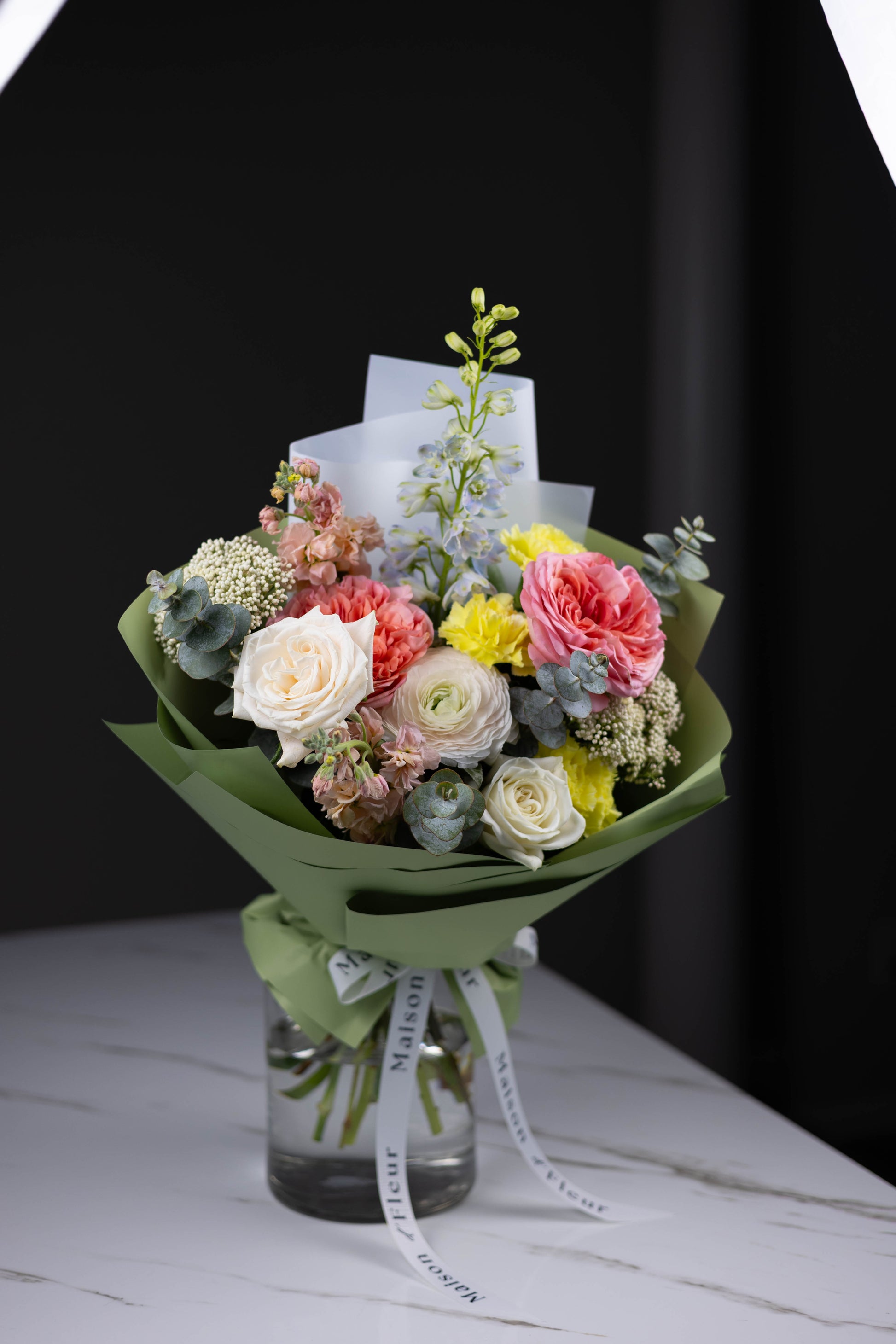 Elegant bouquet featuring blush ranunculus and blue delphinium by Maison d’Fleur