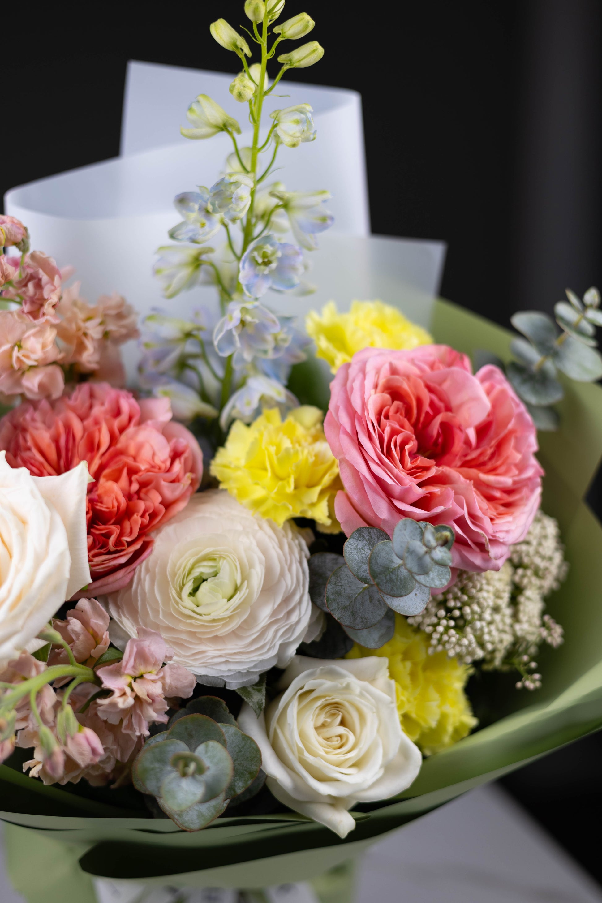 Luxury spring floral arrangement with peach roses, yellow carnations, and delphinium