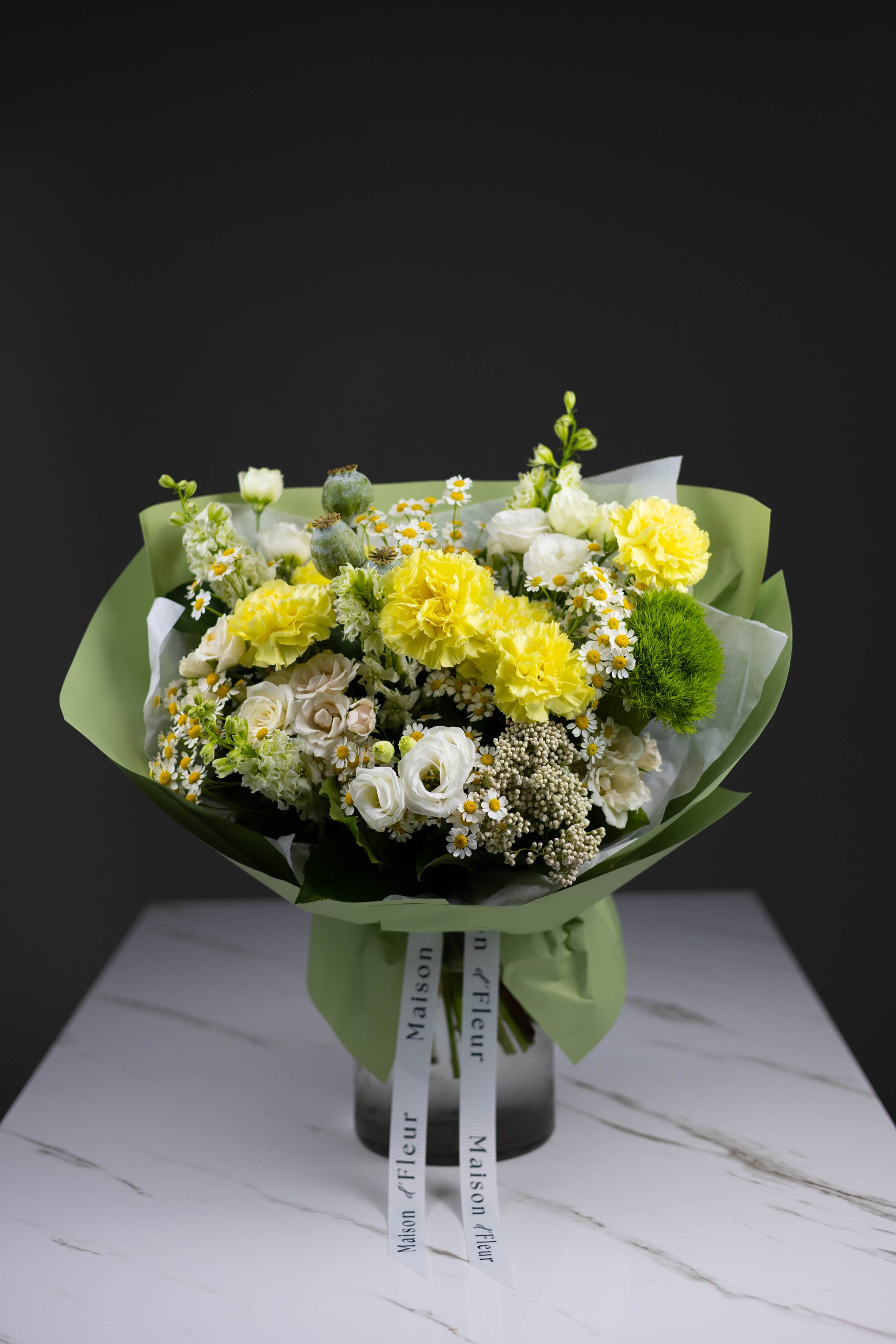 Bright yellow carnations contrast with delicate white lisianthus and playful chamomile flowers in a tightly arranged bouquet — fresh, joyful, and rustic-chic in style.