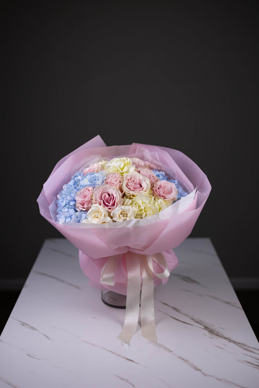 Blush and baby blue bouquet viewed from above, tied with ivory bow