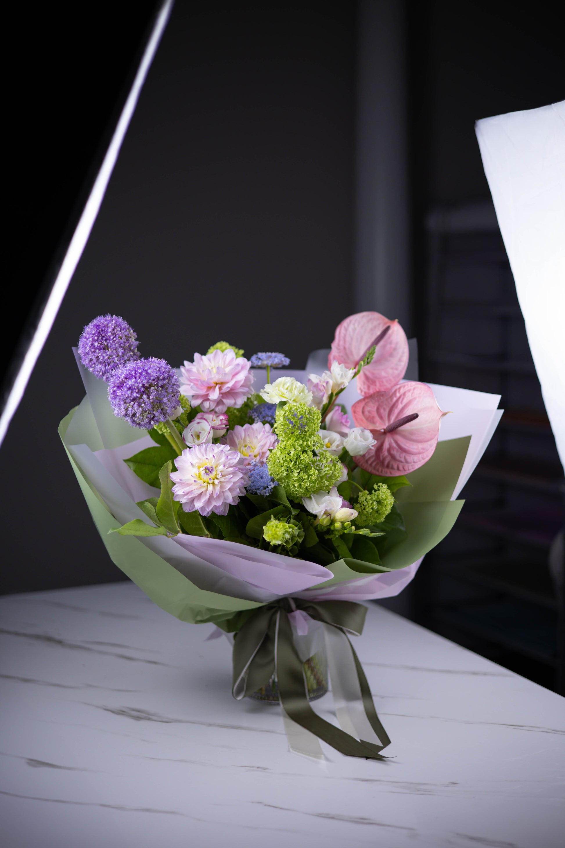 Angled view of the pastel bouquet showcasing anthuriums and dahlias