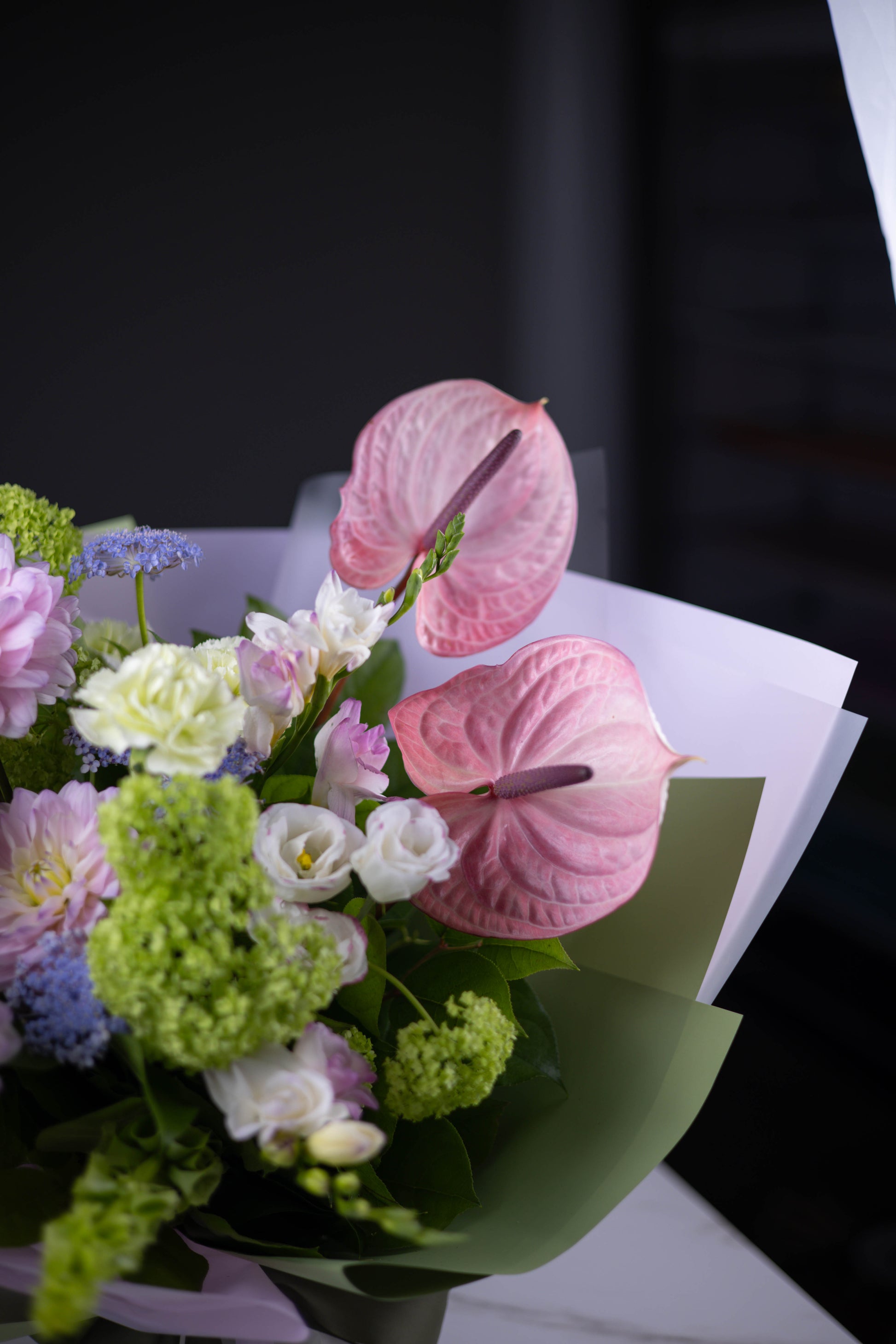 Close-up of pink anthuriums with lisianthus and viburnum in a pastel bouquet