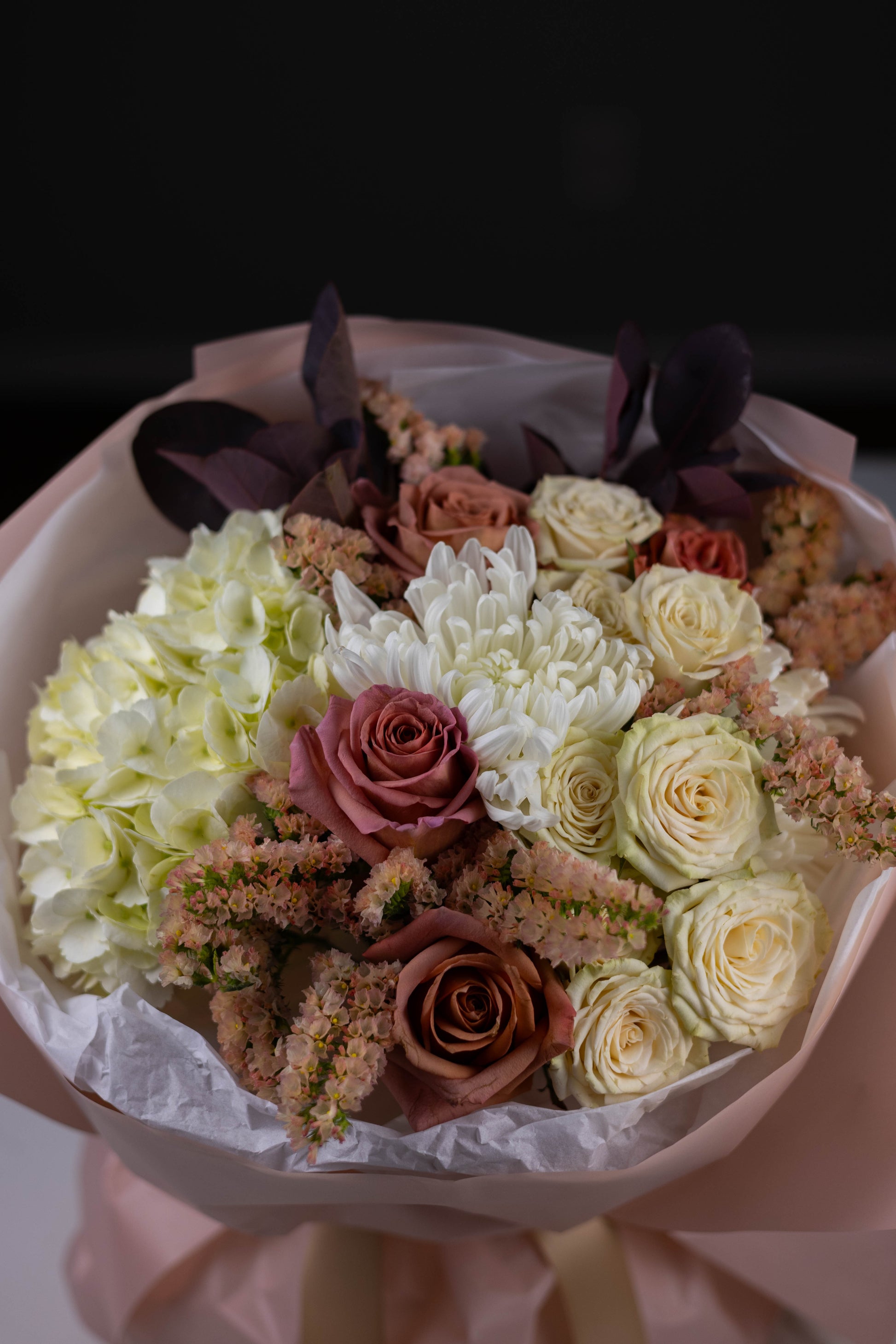 Bouquet of flowers with white, pink, and green colors on a dark background