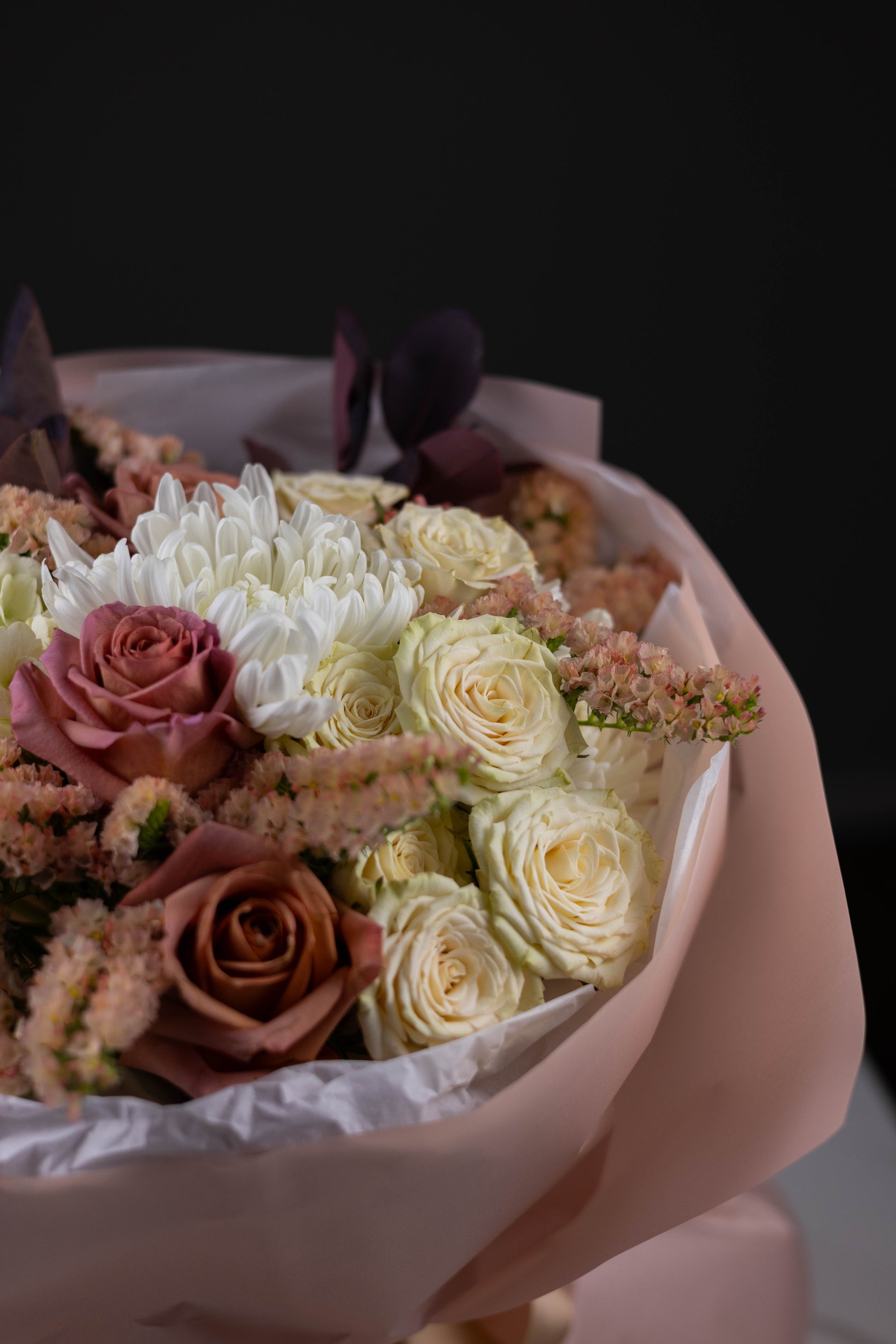 Bouquet of flowers wrapped in white paper with a dark background