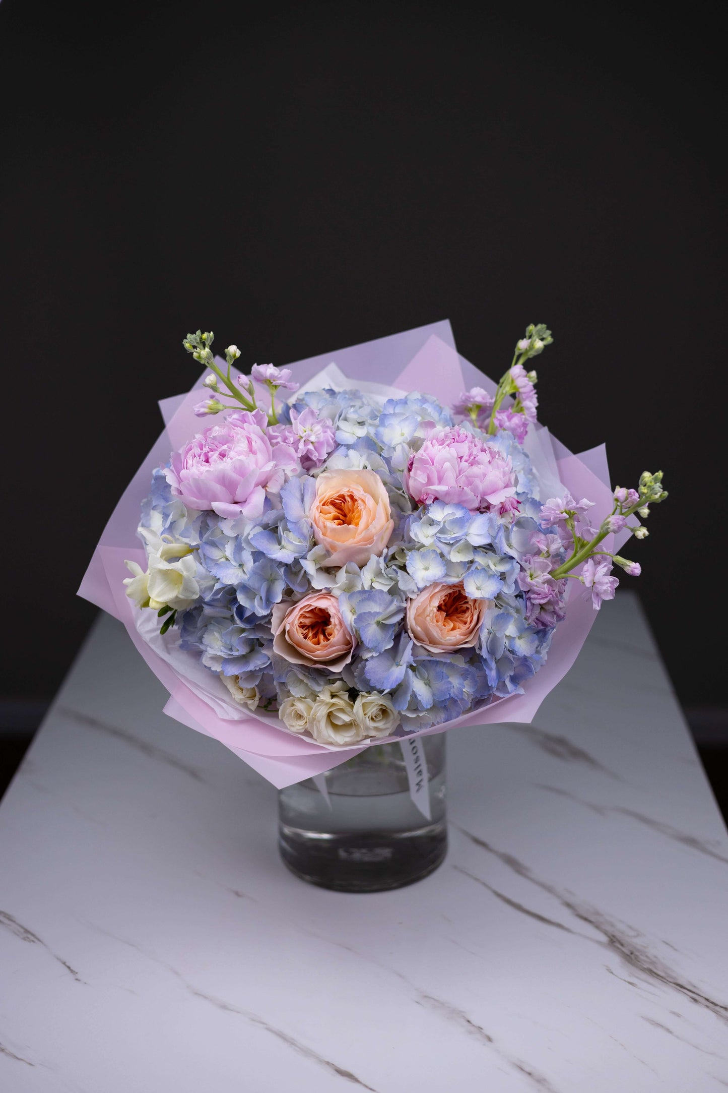 Elegant pastel bouquet with peach roses and blue flowers for premium flower delivery in Charlotte North Carolina