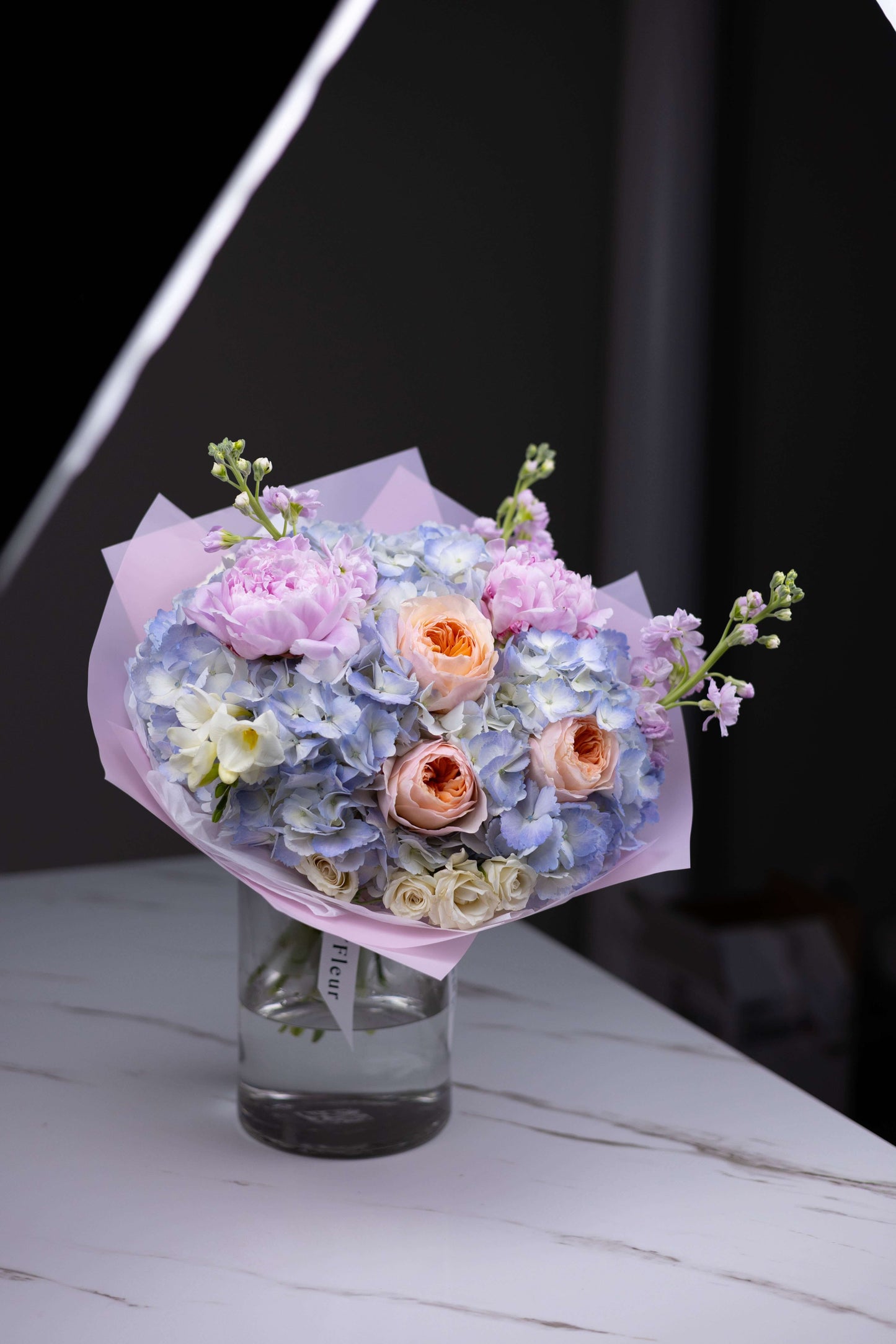 High-end floral arrangement featuring blush roses, lavender stock, and hydrangeas by luxury florist