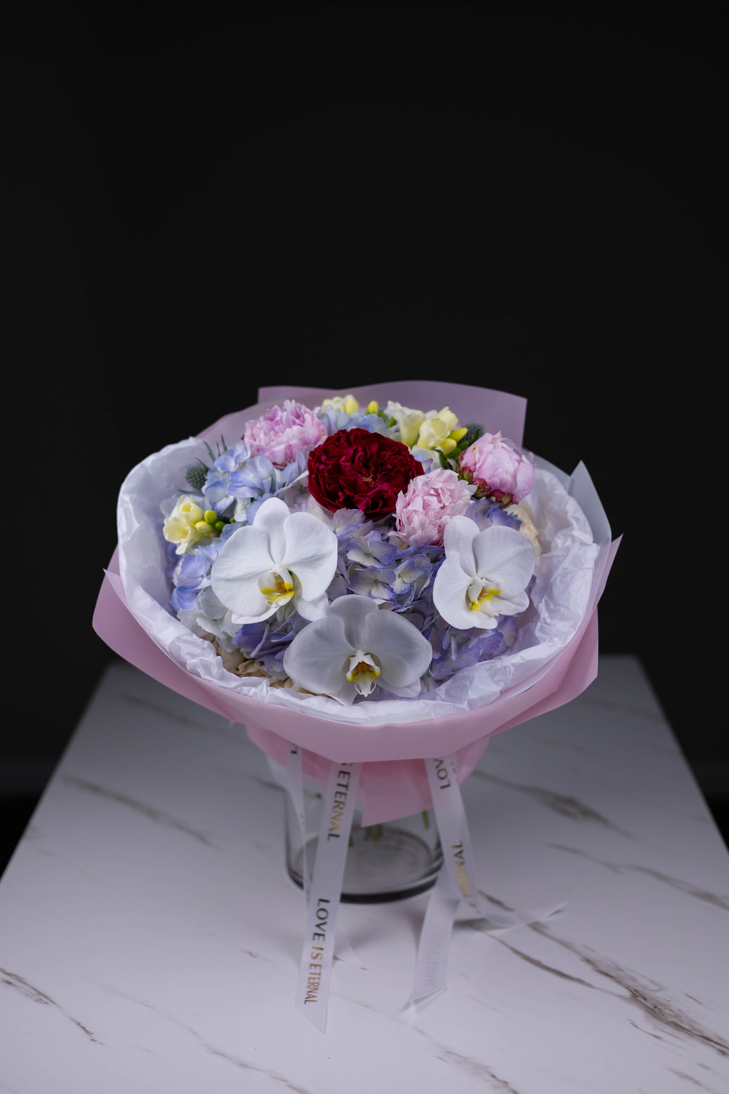 Luxury flower bouquet with red garden roses, white orchids, and blue hydrangeas by Maison d’Fleur Charlotte