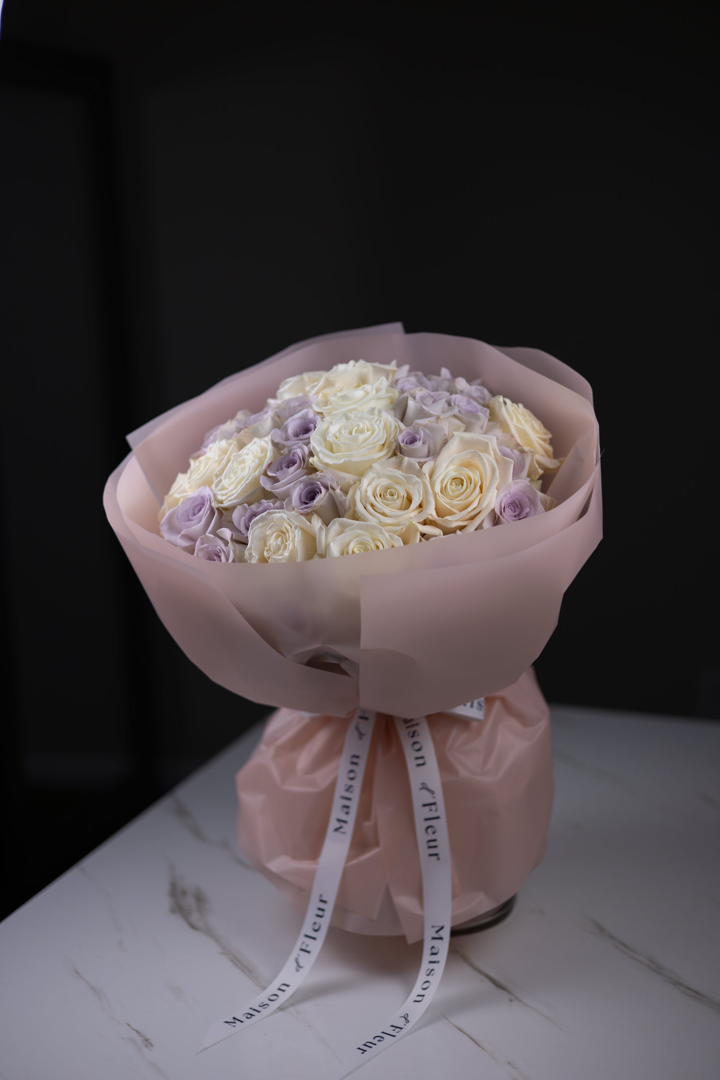 Side view of a pastel rose bouquet showing the mix of ivory and lavender blooms.