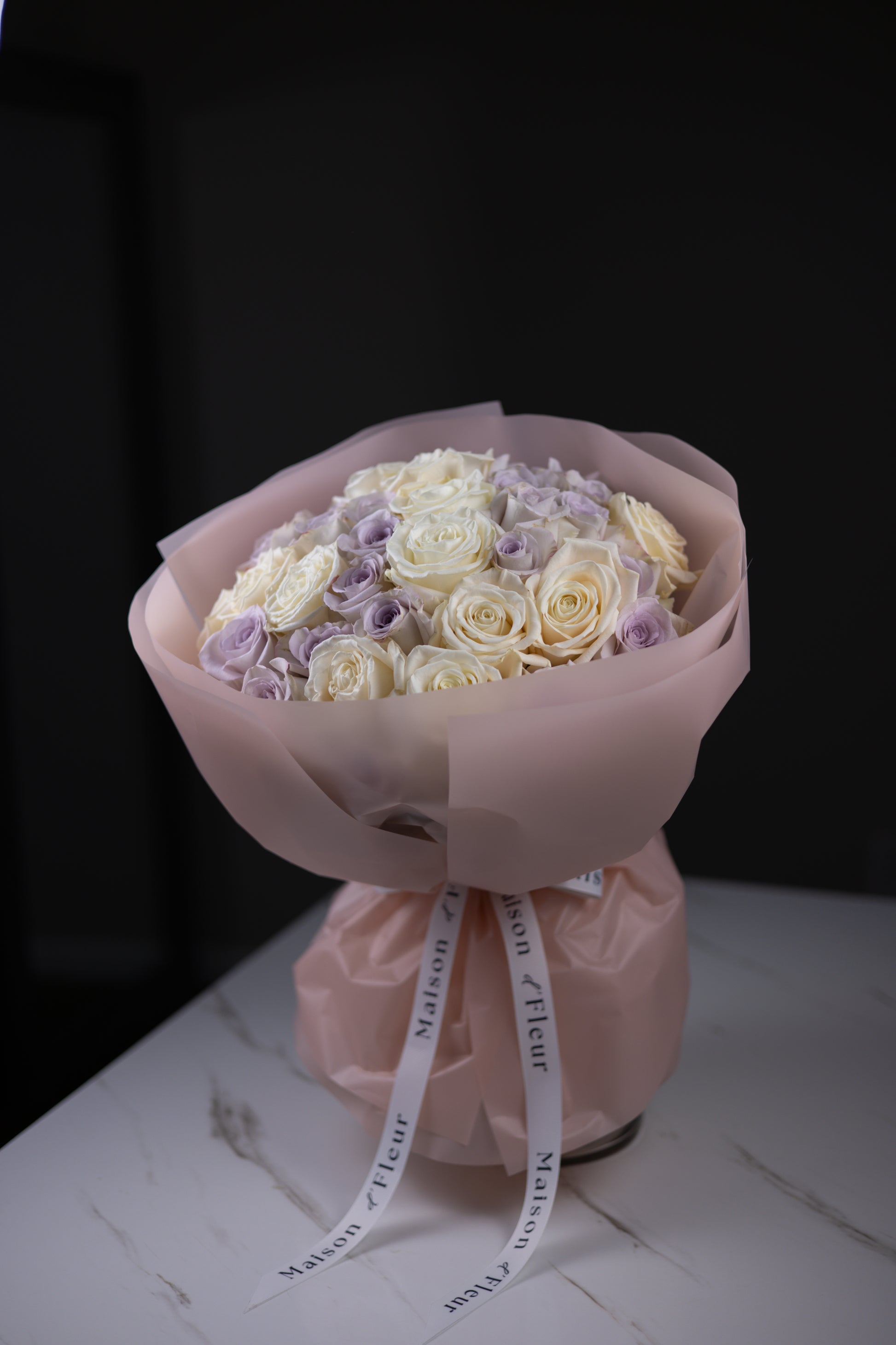 Side view of a pastel rose bouquet showing the mix of ivory and lavender blooms.