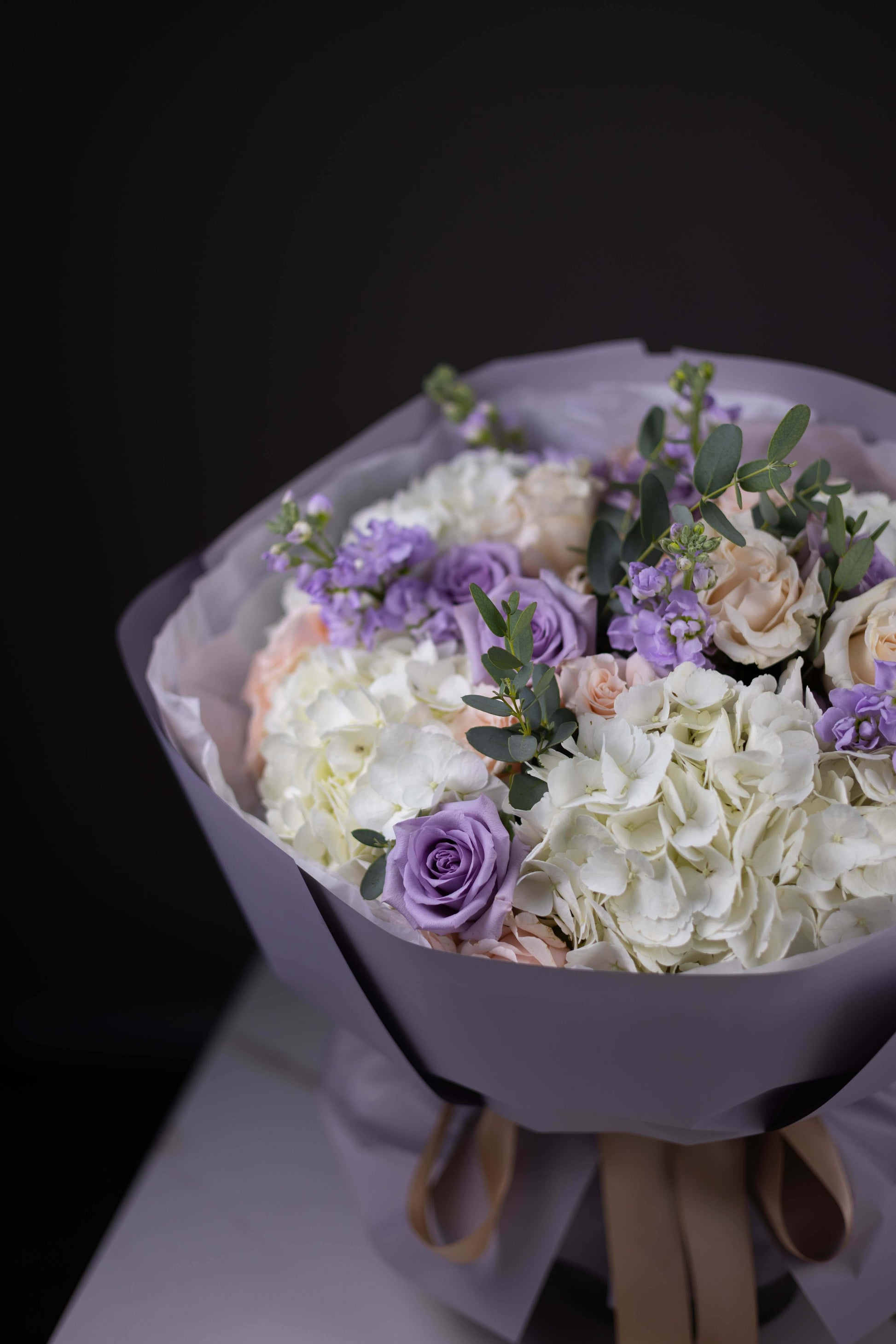 Bouquet of flowers with white, purple, and green elements on a dark background