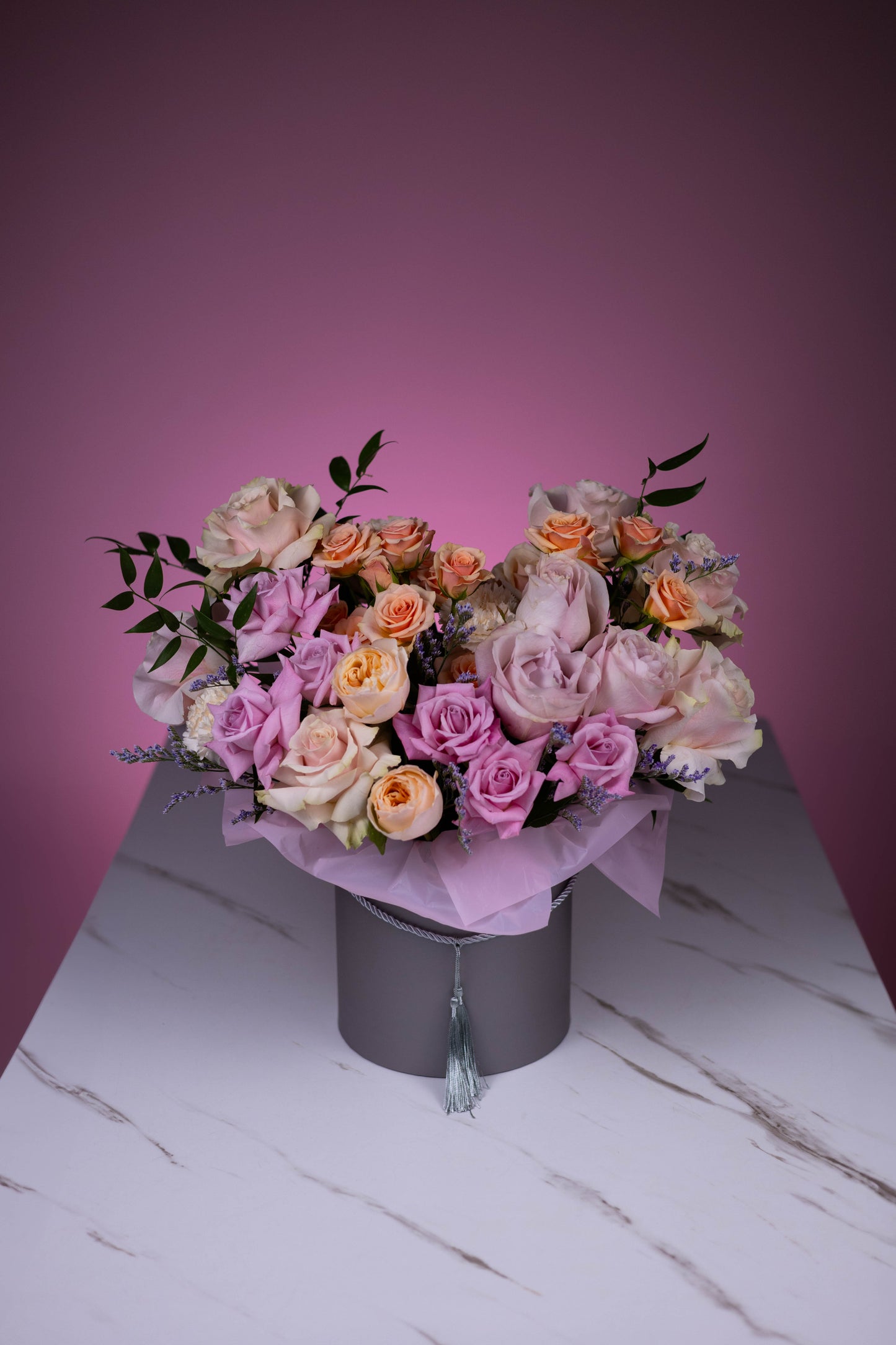 Bouquet of flowers in a black box against a pink background