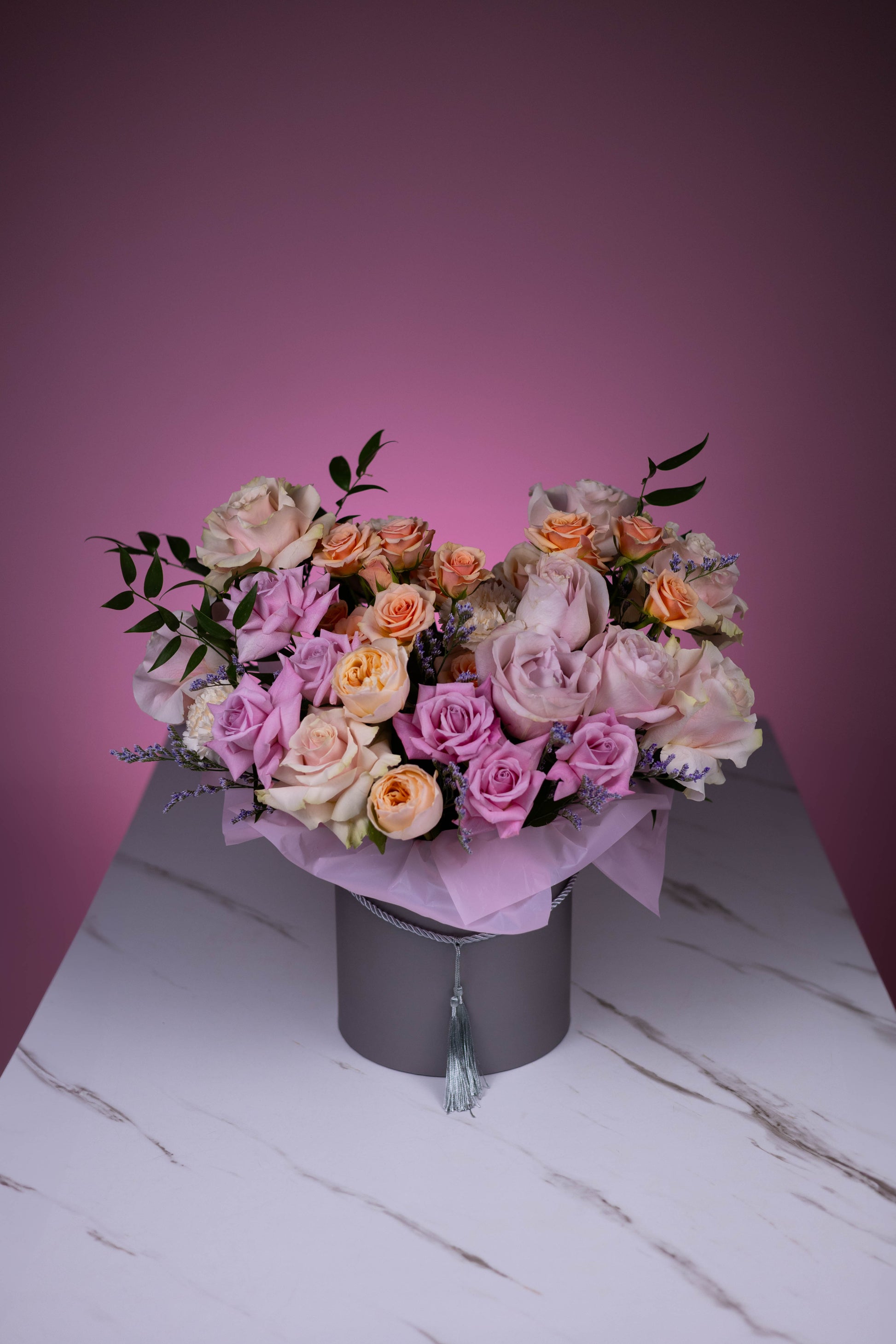 Bouquet of flowers in a black box against a pink background