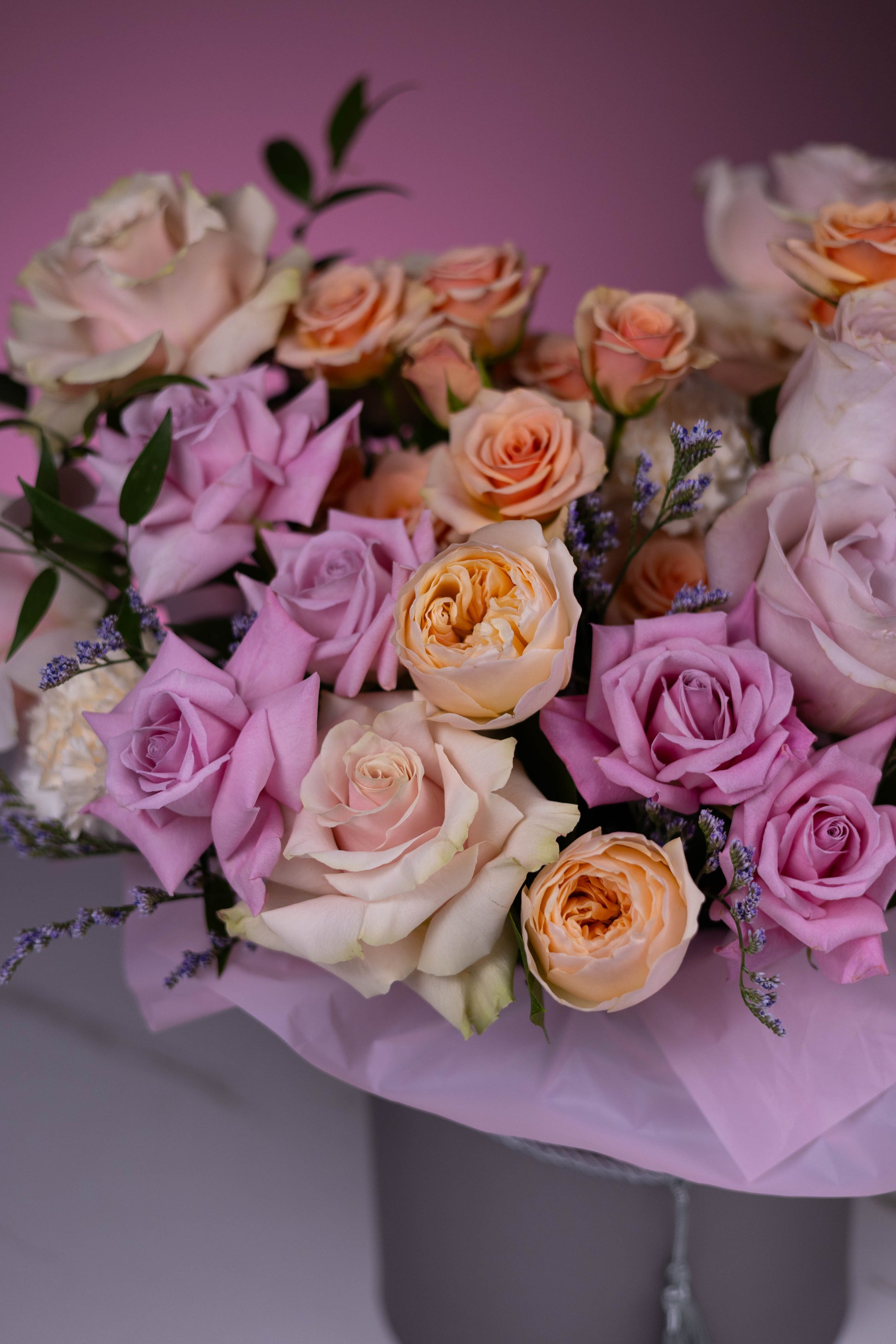 Bouquet of pink, purple, and orange roses on a pink background