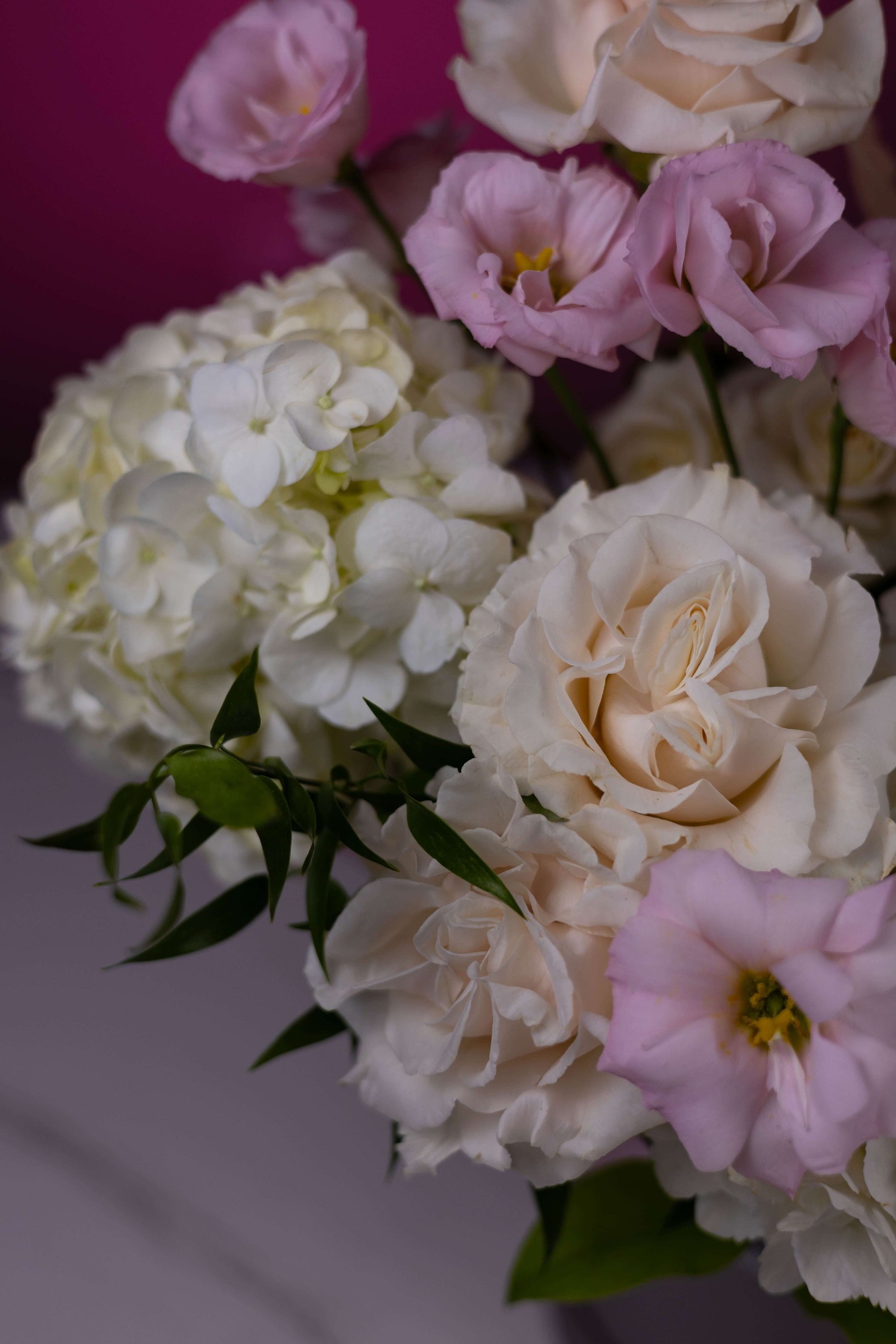 Bouquet of white, pink, and cream flowers against a pink background