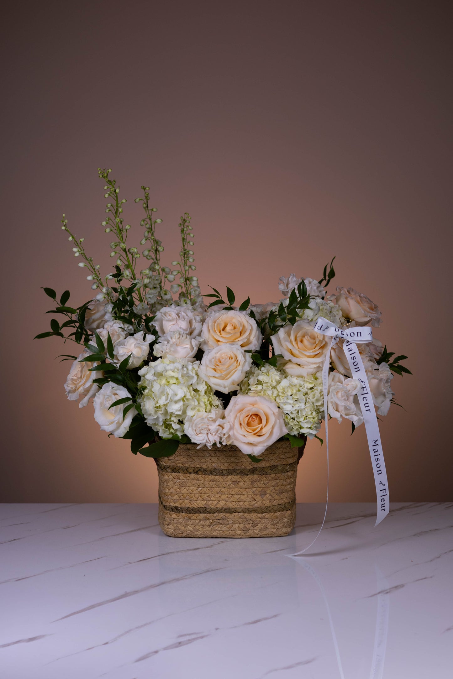 Creamy ivory bouquet of roses, hydrangeas, and lisianthus arranged in a woven basket