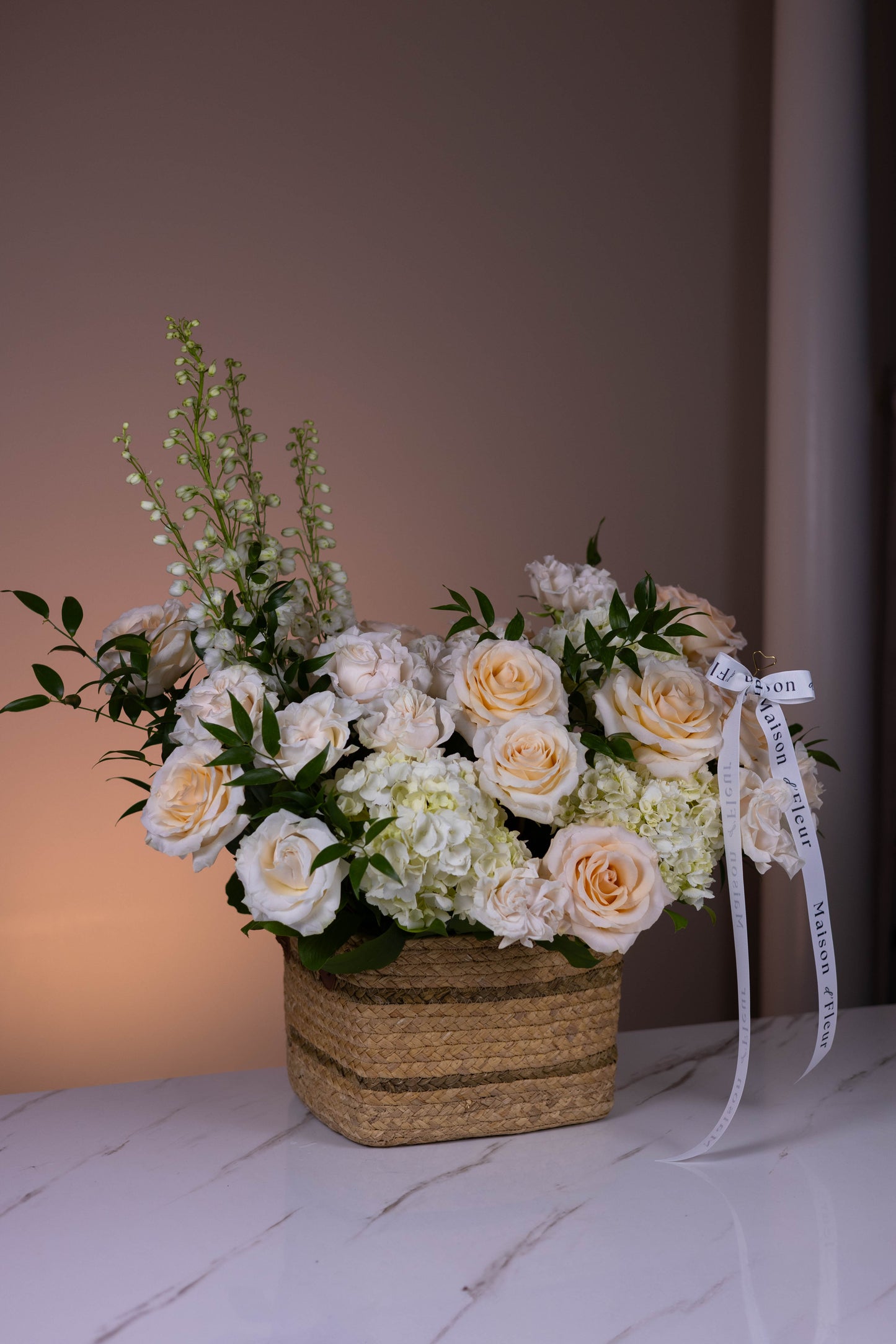 Floral arrangement in a woven basket with a ribbon on a wooden surface.