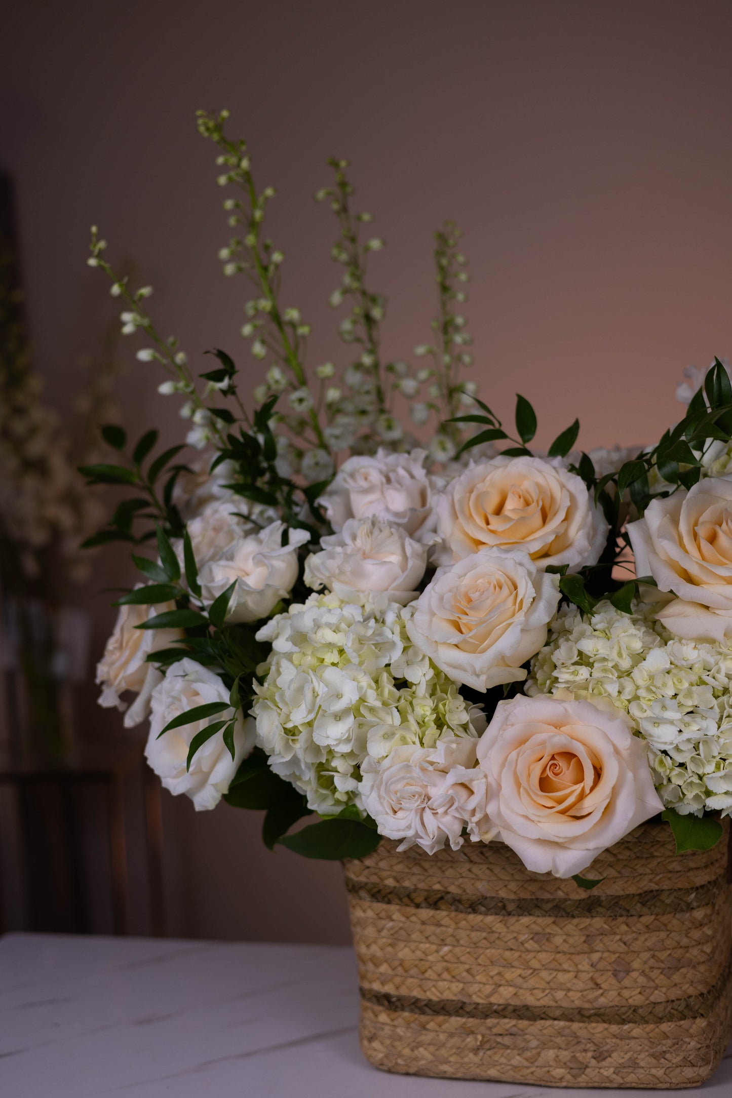 Bouquet of flowers in a woven basket on a table with a blurred background