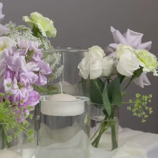 Floral arrangement with small vases on a marble surface against a dark background