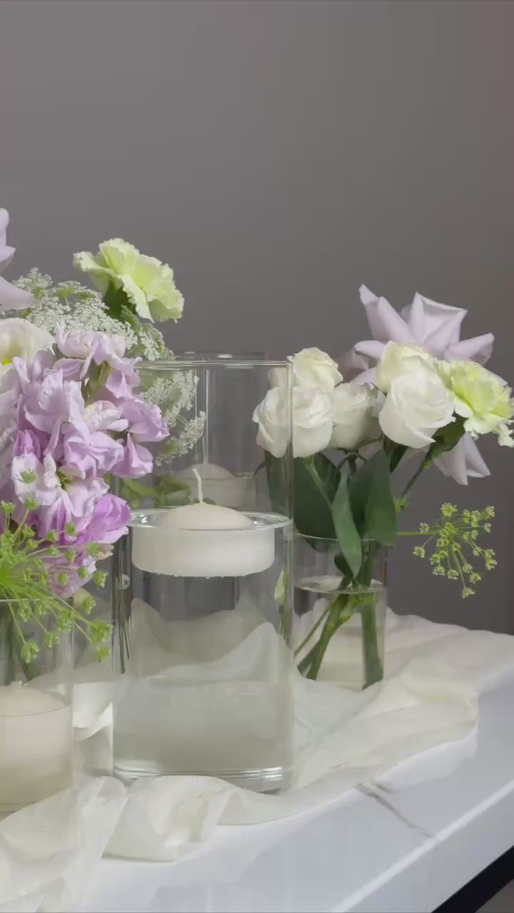 Floral arrangement with small vases on a marble surface against a dark background