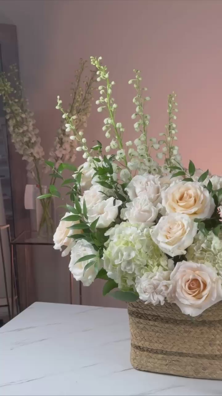 Elegant ivory bouquet styled in a rustic basket with soft evening lighting